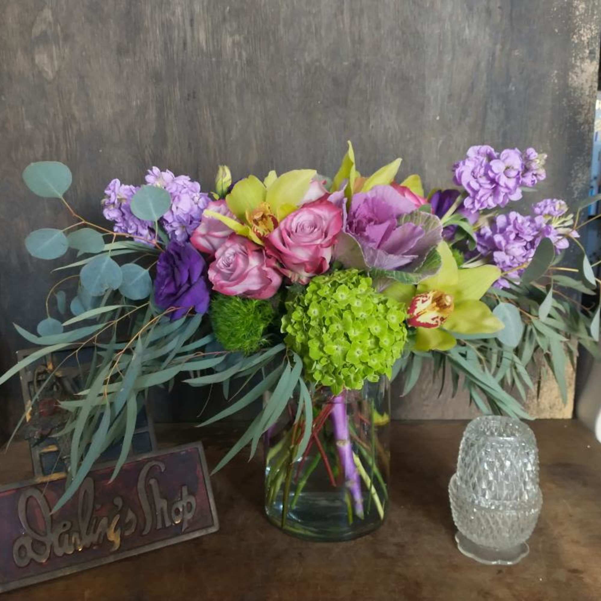 Mixed bouquet of pink, purple, and green flowers in a glass vase