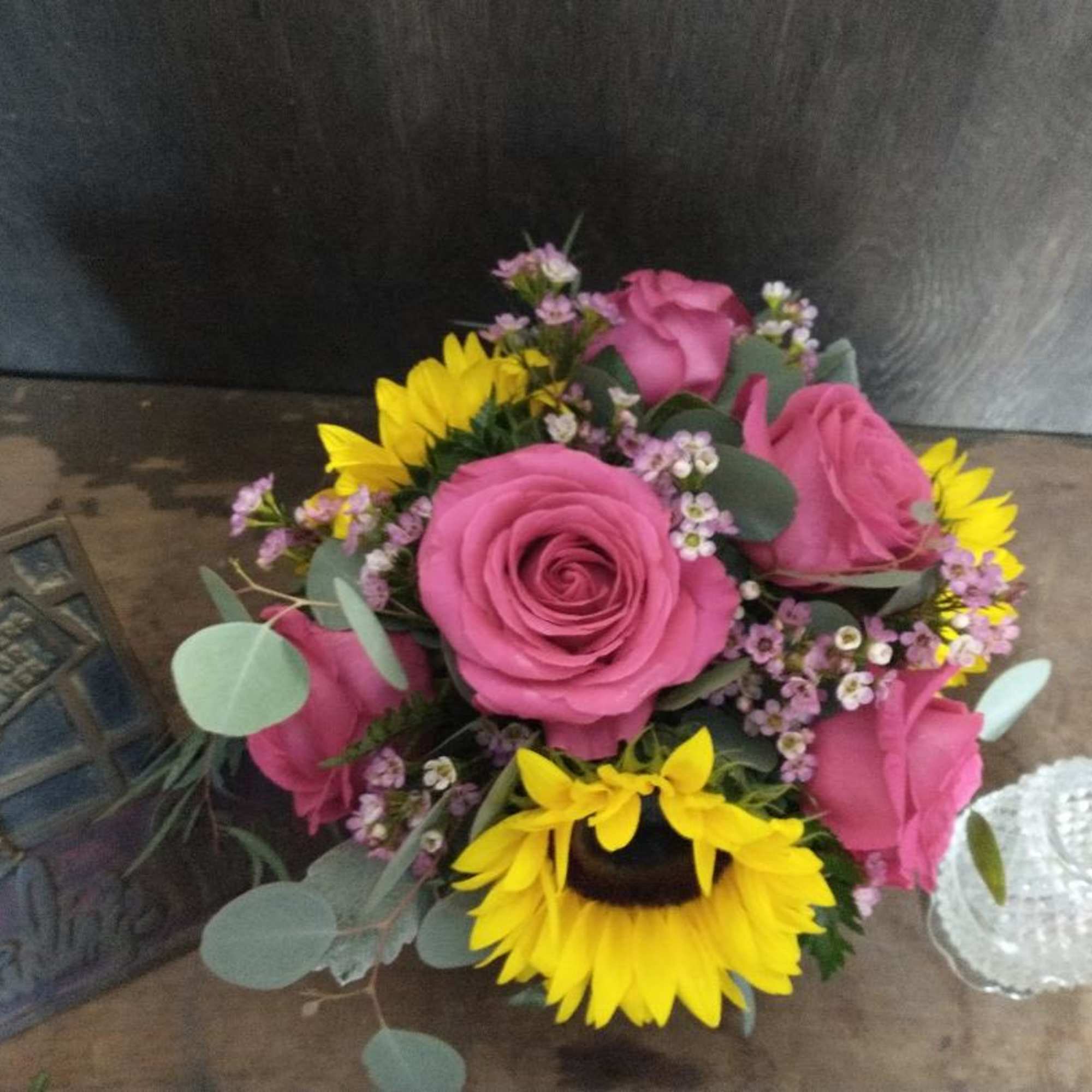 Pink roses and yellow sunflowers arranged in a low bouquet