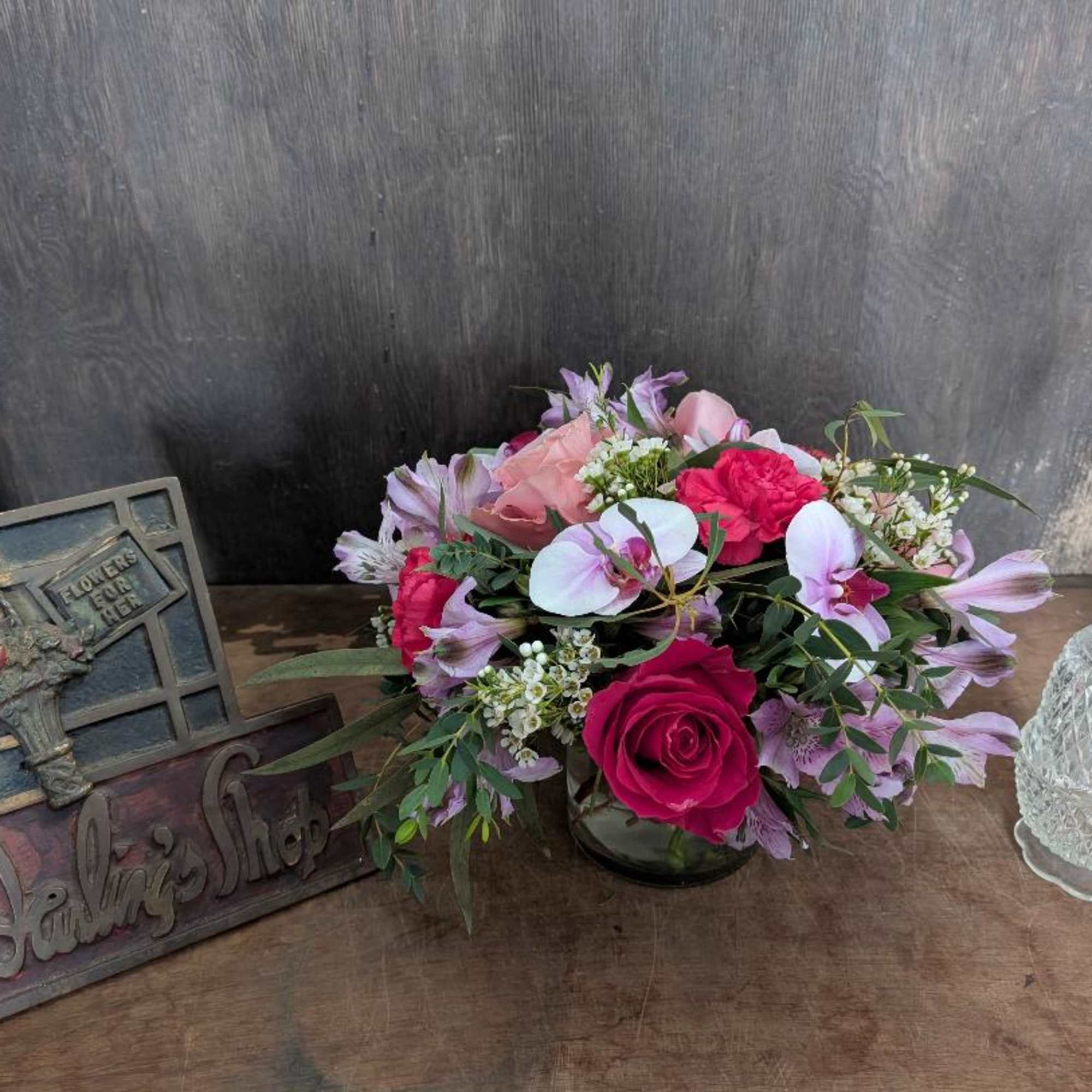 Pink and lavender flower arrangement in a glass vase on a table