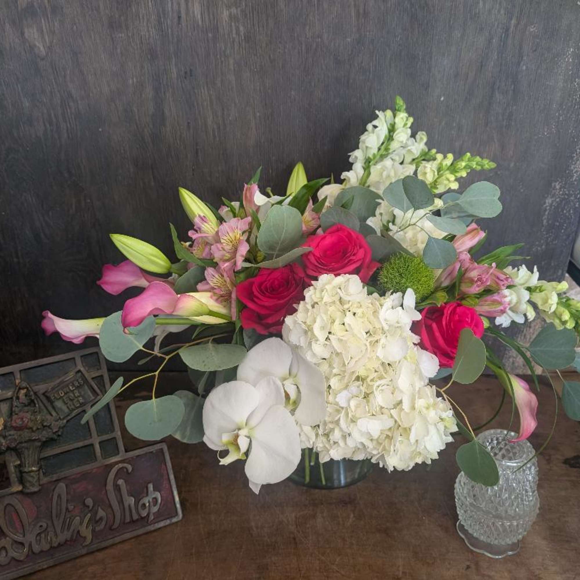 Bouquet of pink roses, white hydrangea, calla lilies, and orchids in a vase