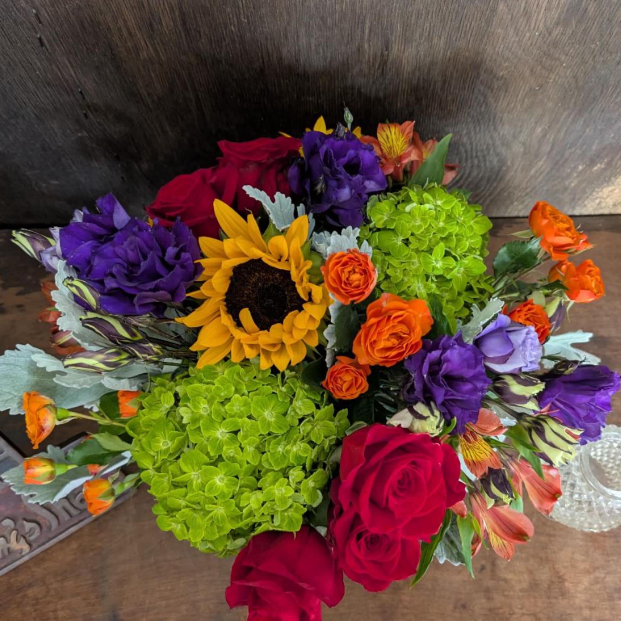 Colorful bouquet with roses, sunflowers, purple blooms, and green hydrangeas