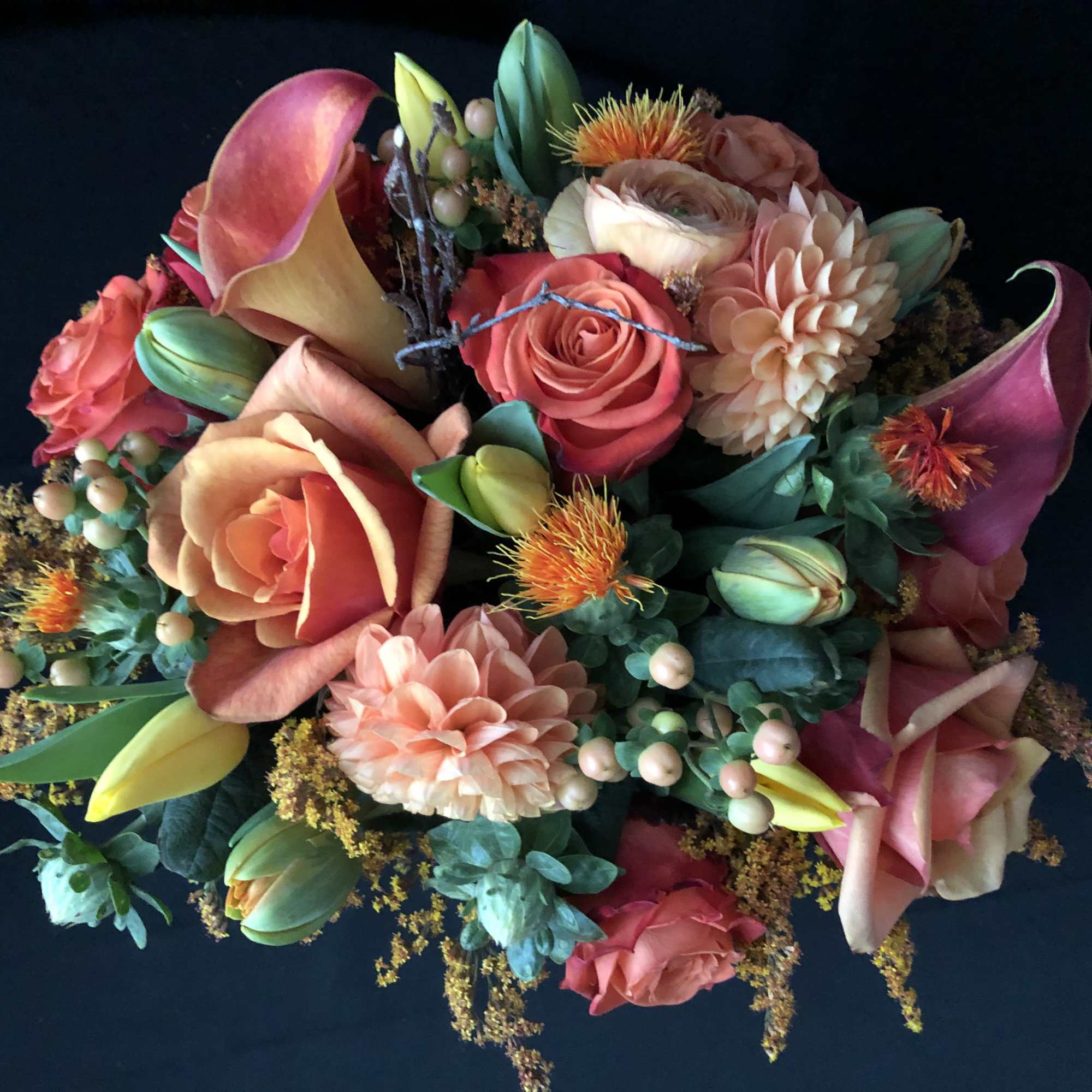 Colorful bouquet with roses, calla lilies, and dahlias on a dark background