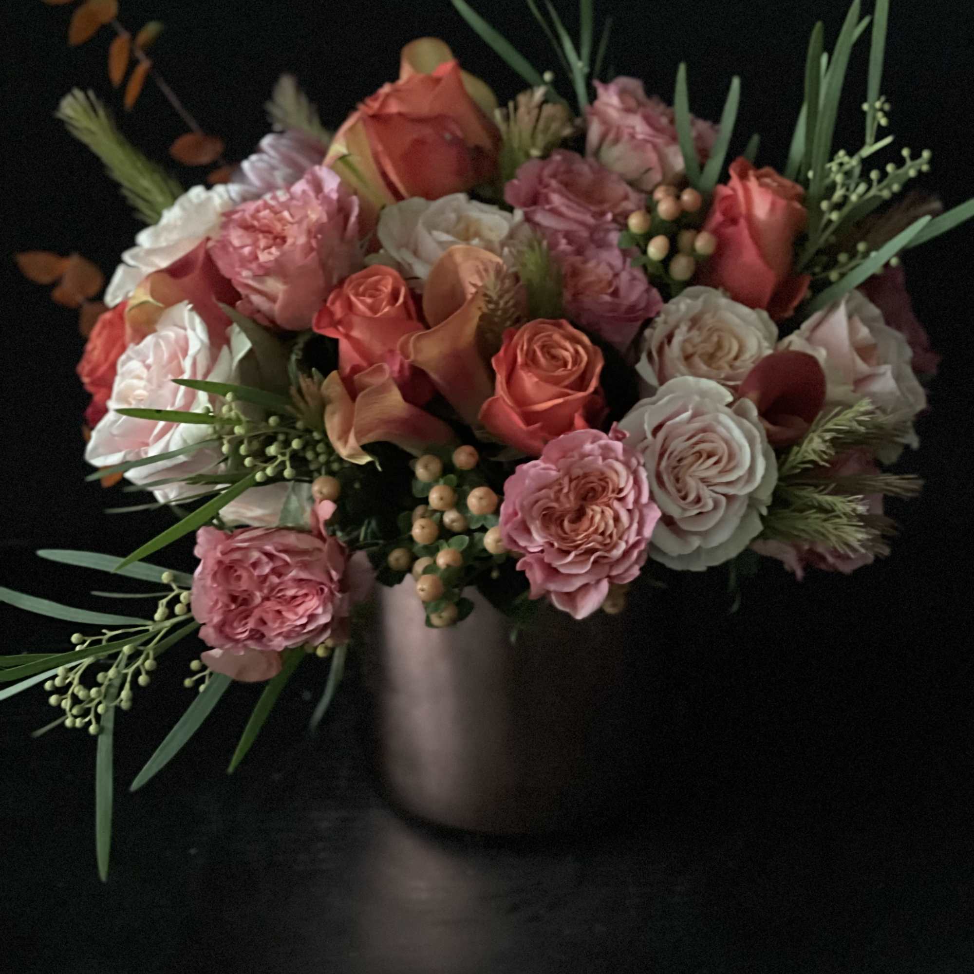Pink and coral rose bouquet in a vase on a dark background