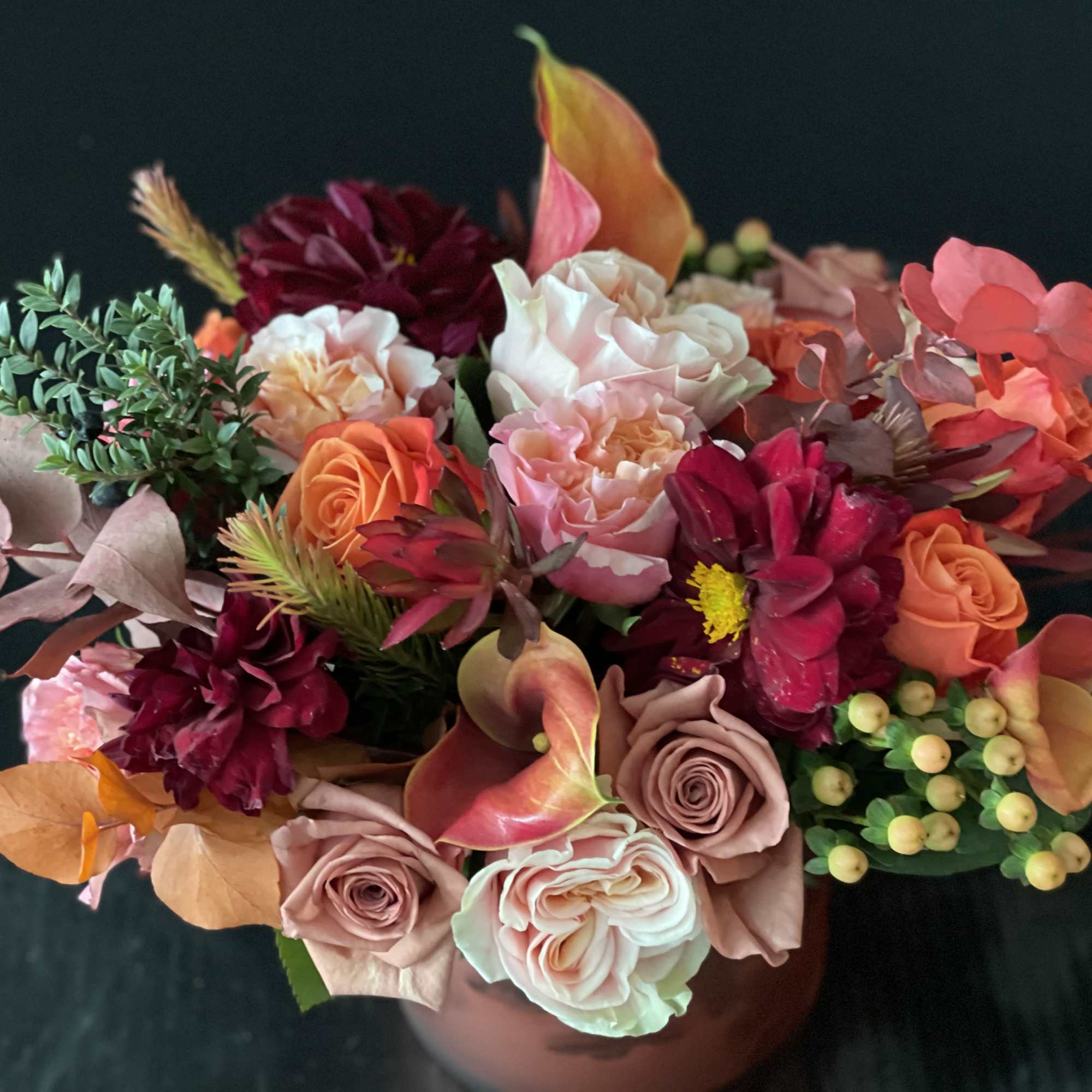 Mixed bouquet of roses, calla lilies, and dark dahlias in a vase