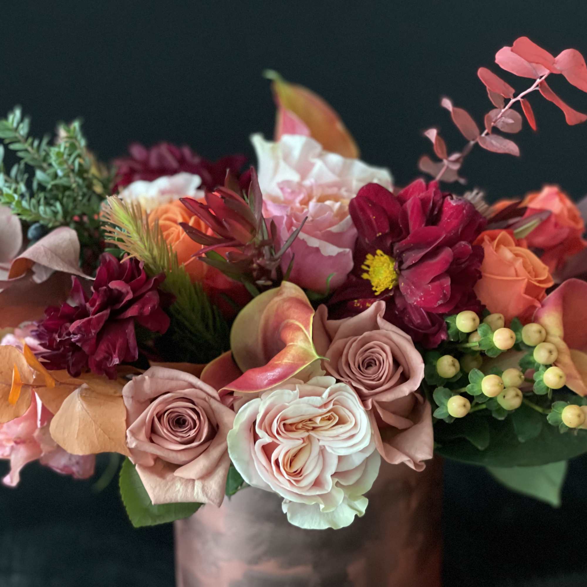 Mixed bouquet of pink, peach, and burgundy flowers in a vase