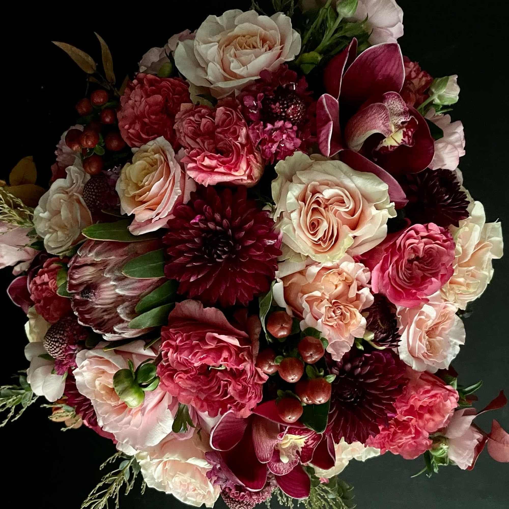 Bouquet of pink, cream, and burgundy flowers on a dark background