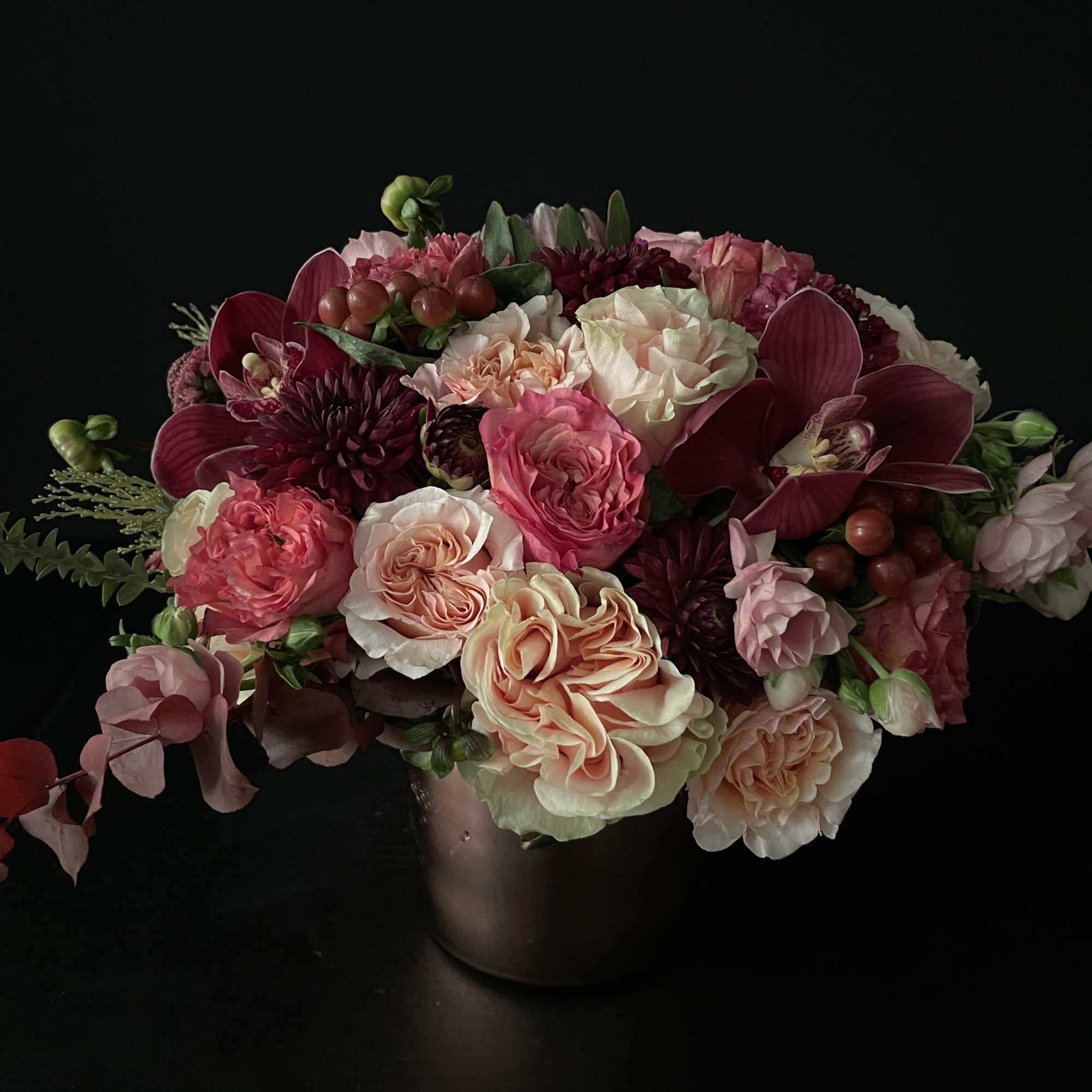 Pink and burgundy floral arrangement in a dark vase