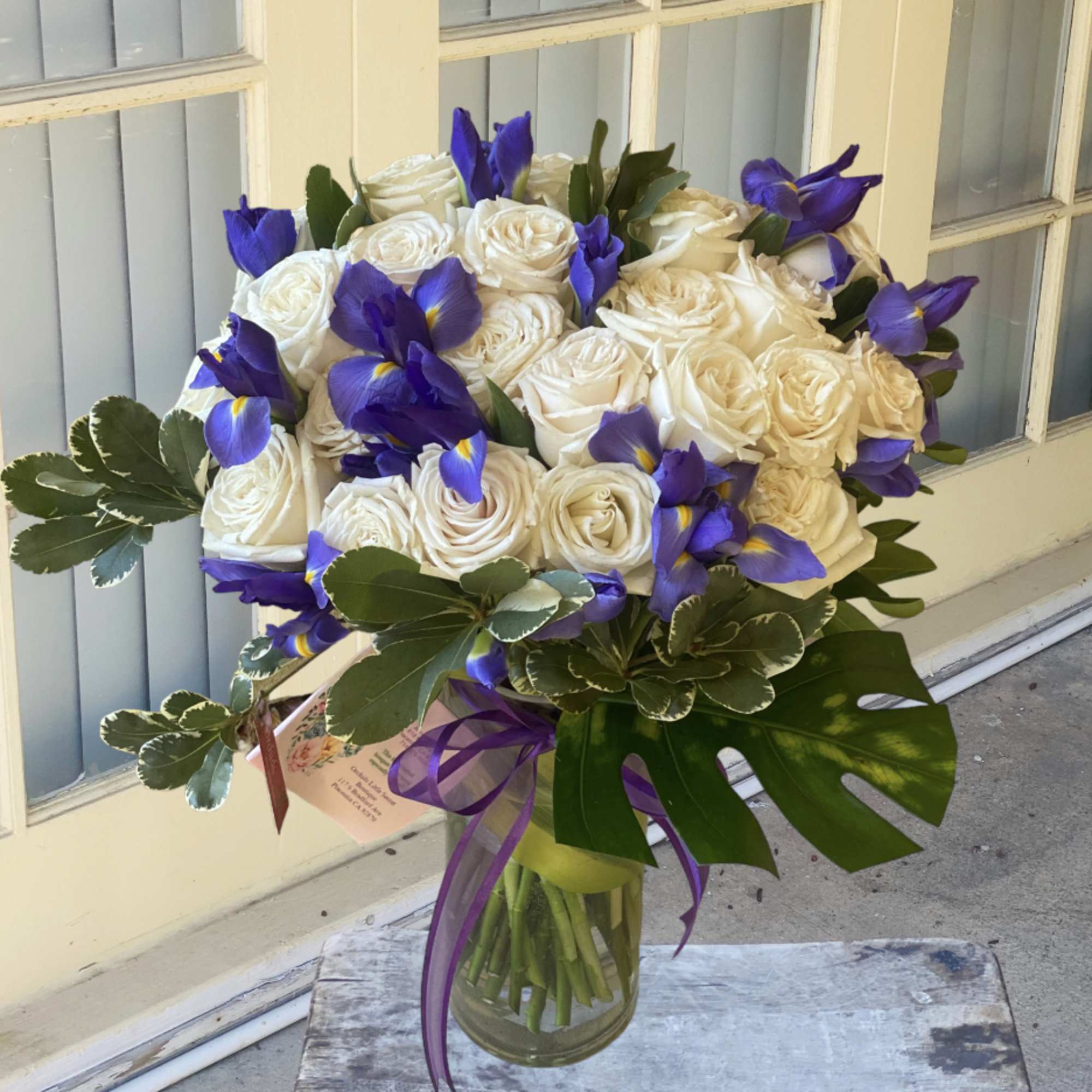 Bouquet of white roses and purple irises in a glass vase