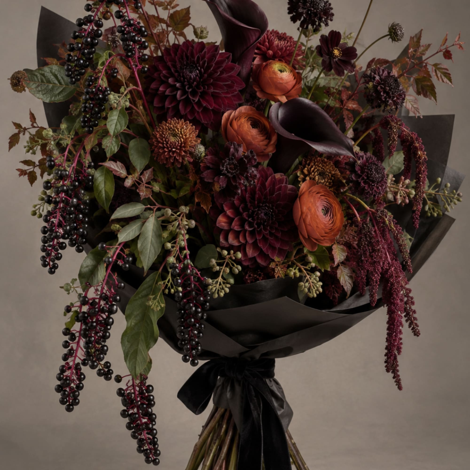 Dark burgundy bouquet with orange blooms and black ribbon wrap