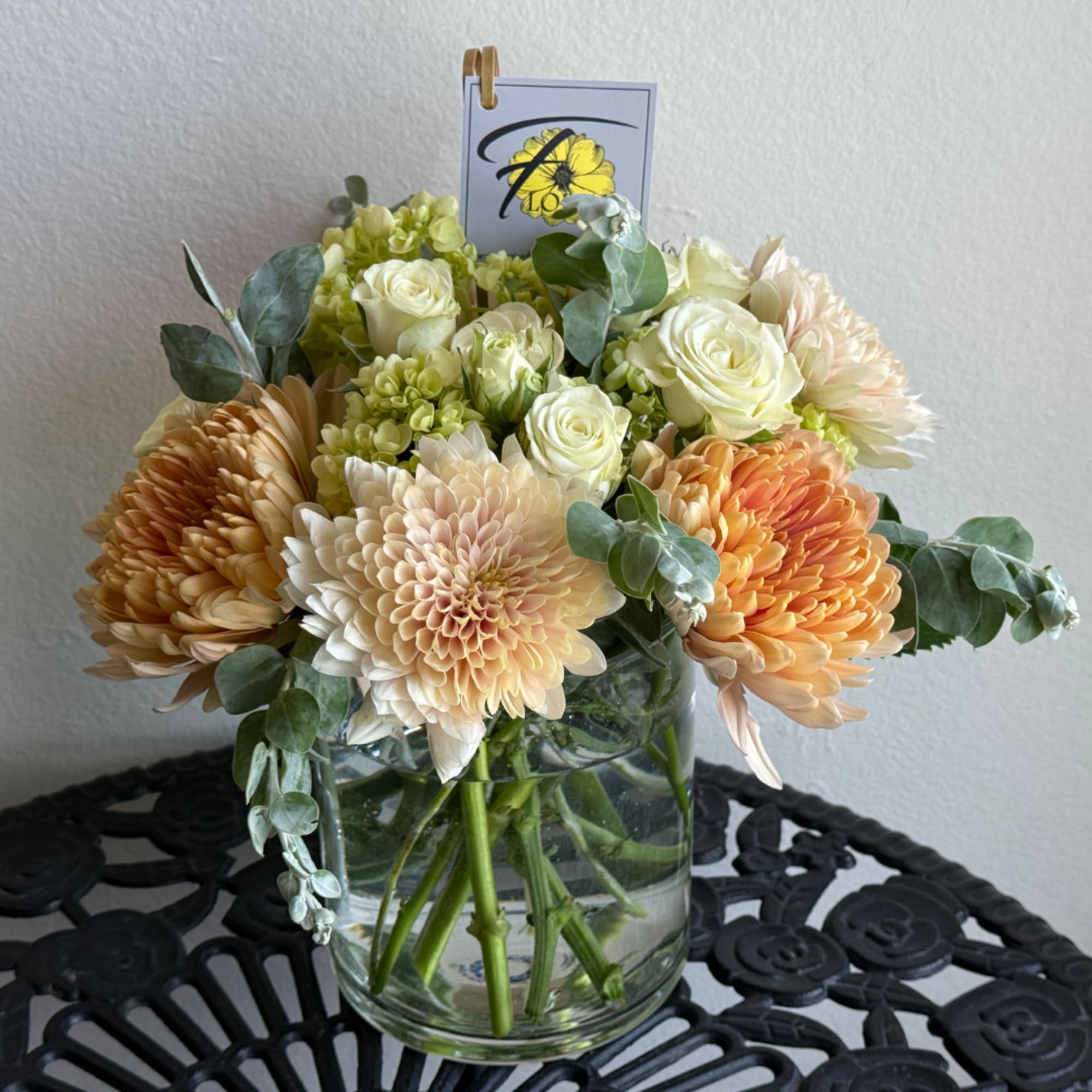 Peach and white flowers arranged in a clear glass vase
