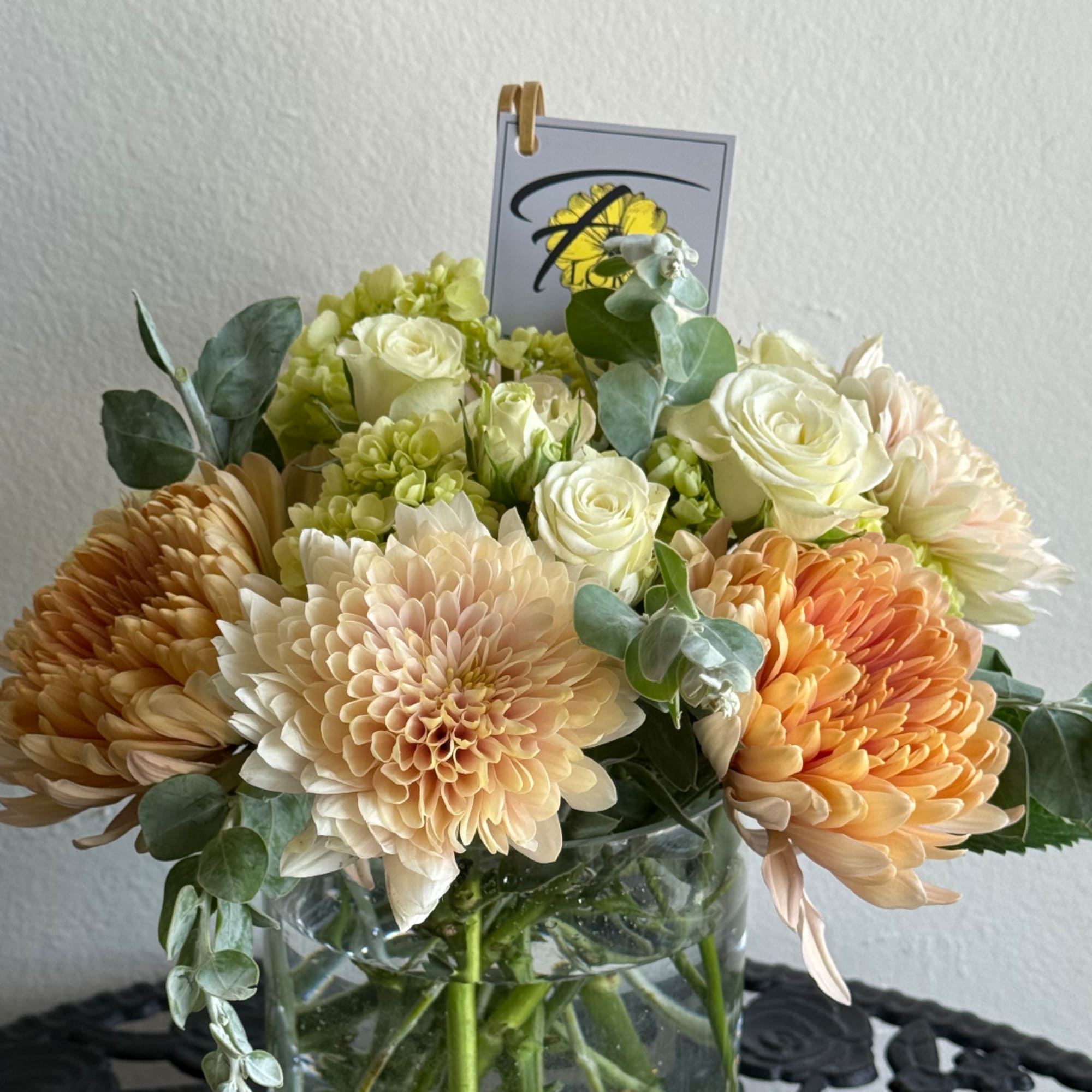 Peach and white flowers arranged in a clear glass vase, photo 2 of 2