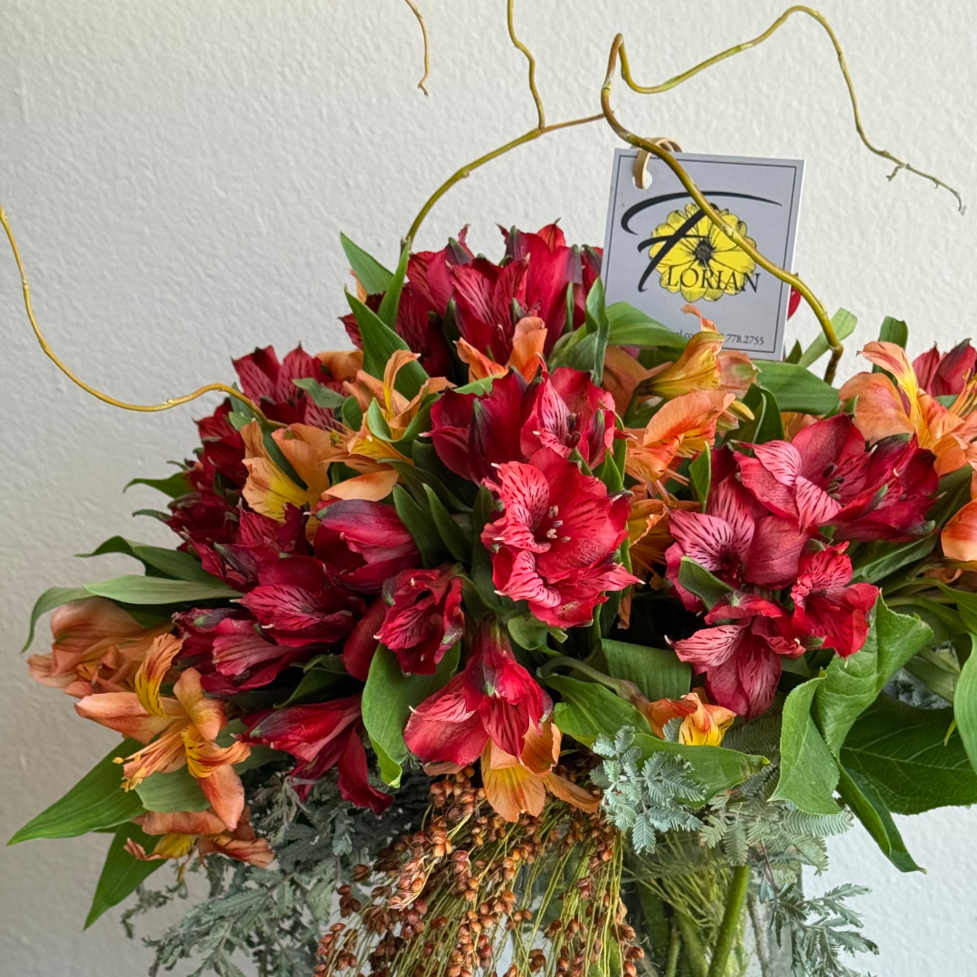 Bouquet of red and orange alstroemeria with greenery in a vase