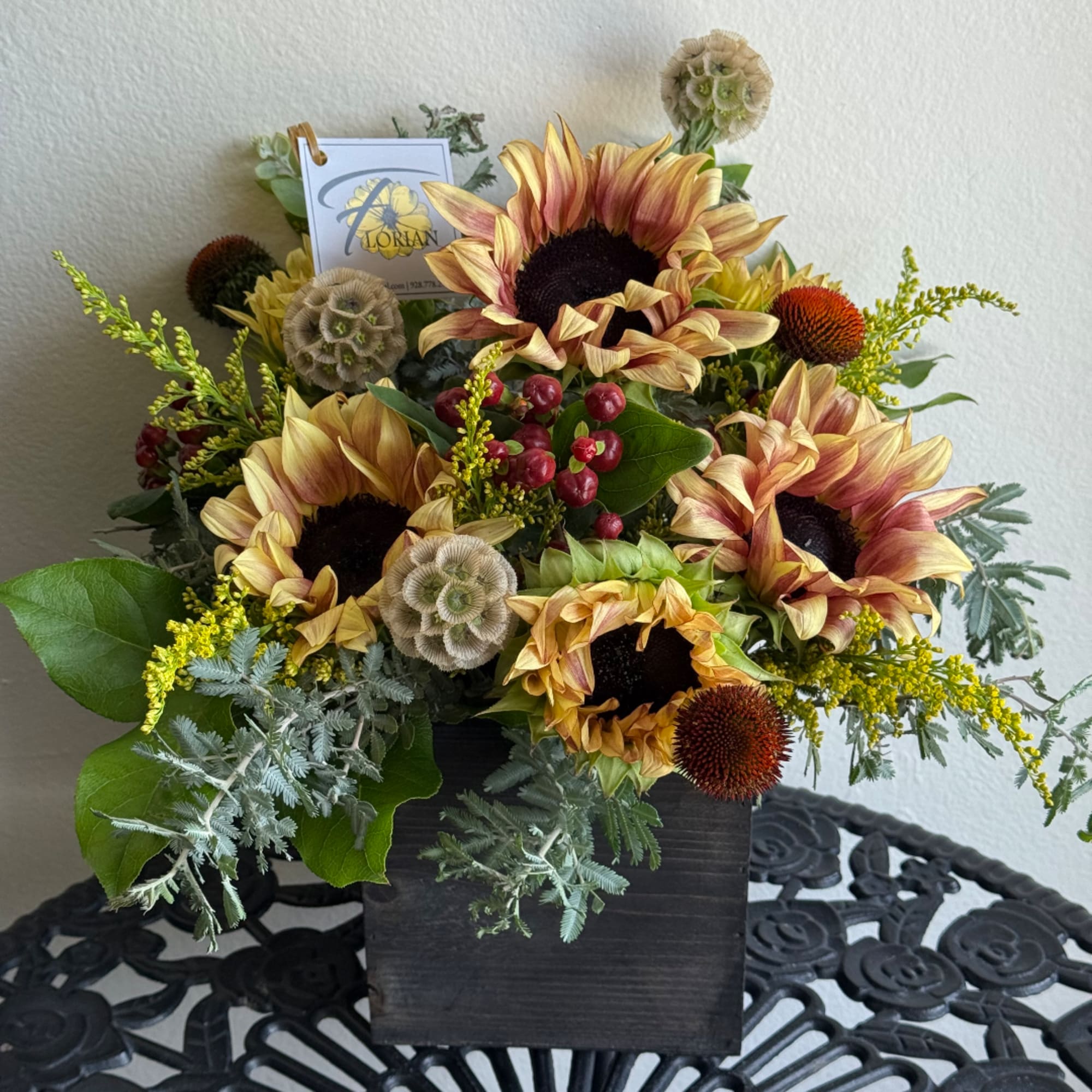 Sunflower arrangement in a black square vase with berries and greenery