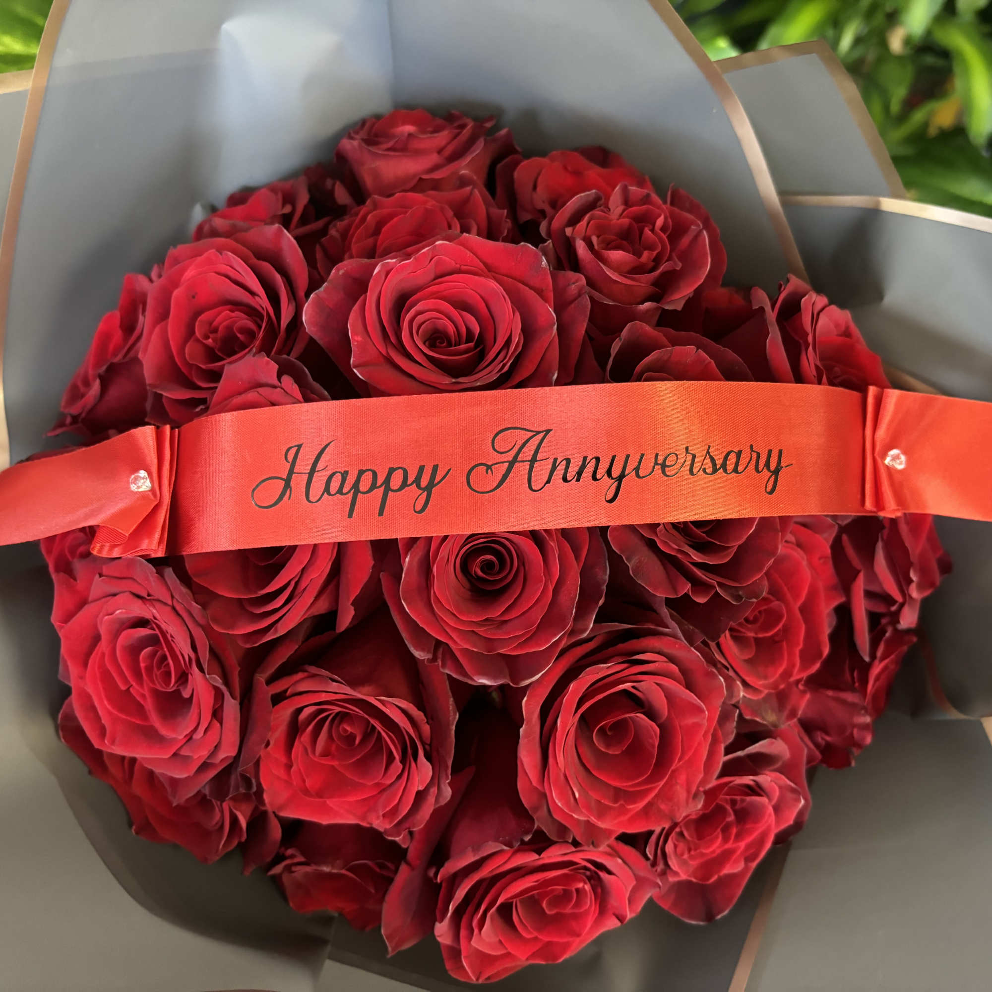 Bouquet of red roses wrapped with a Happy Anniversary ribbon