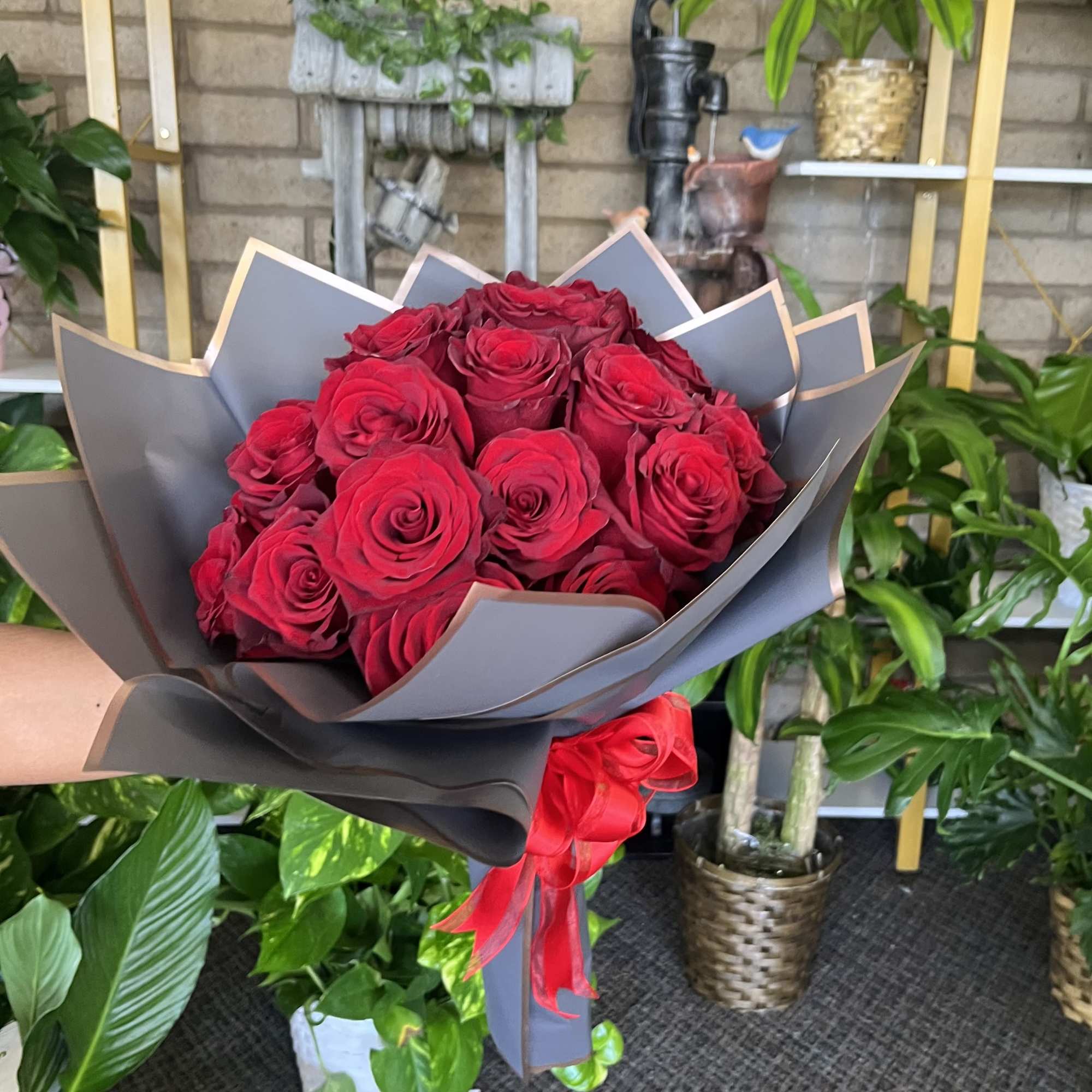 Bouquet of red roses wrapped in gray paper with a red ribbon