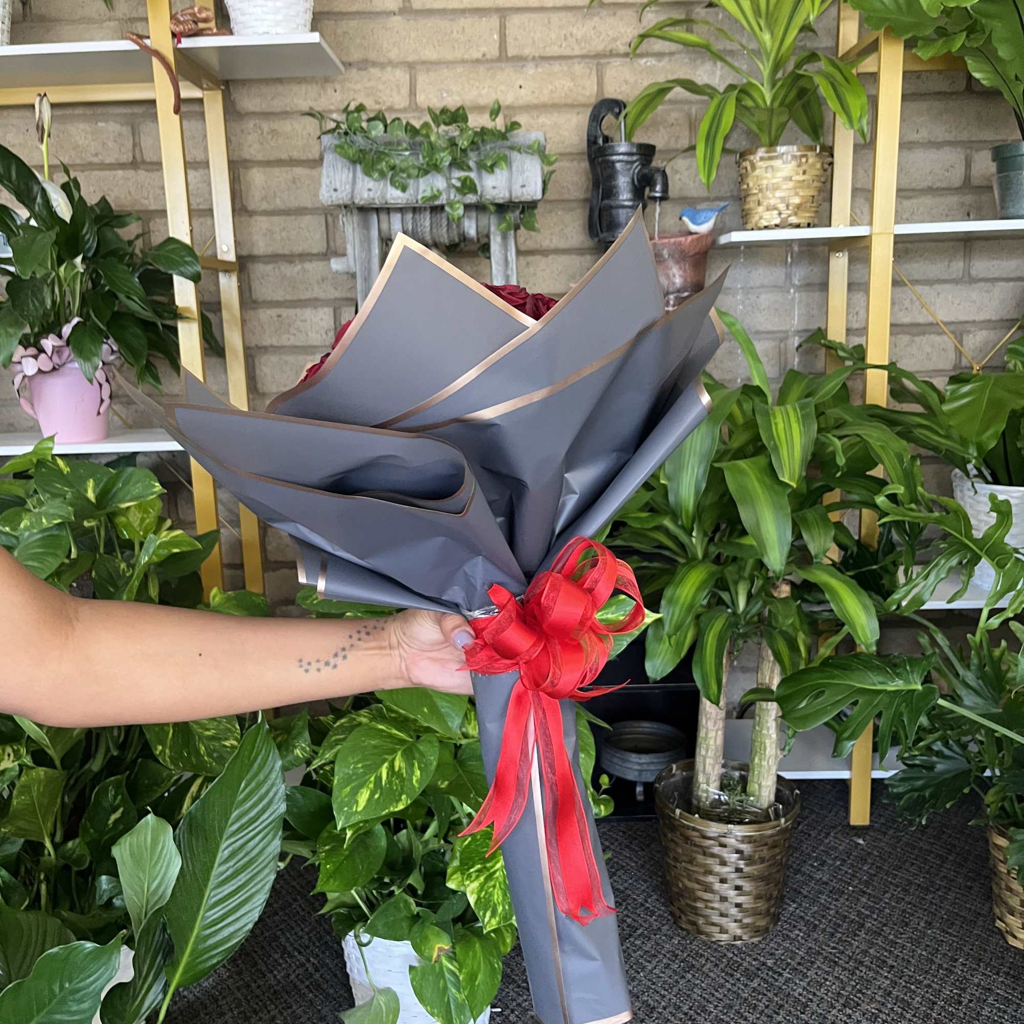 Handheld bouquet wrapped in gray paper with a red ribbon