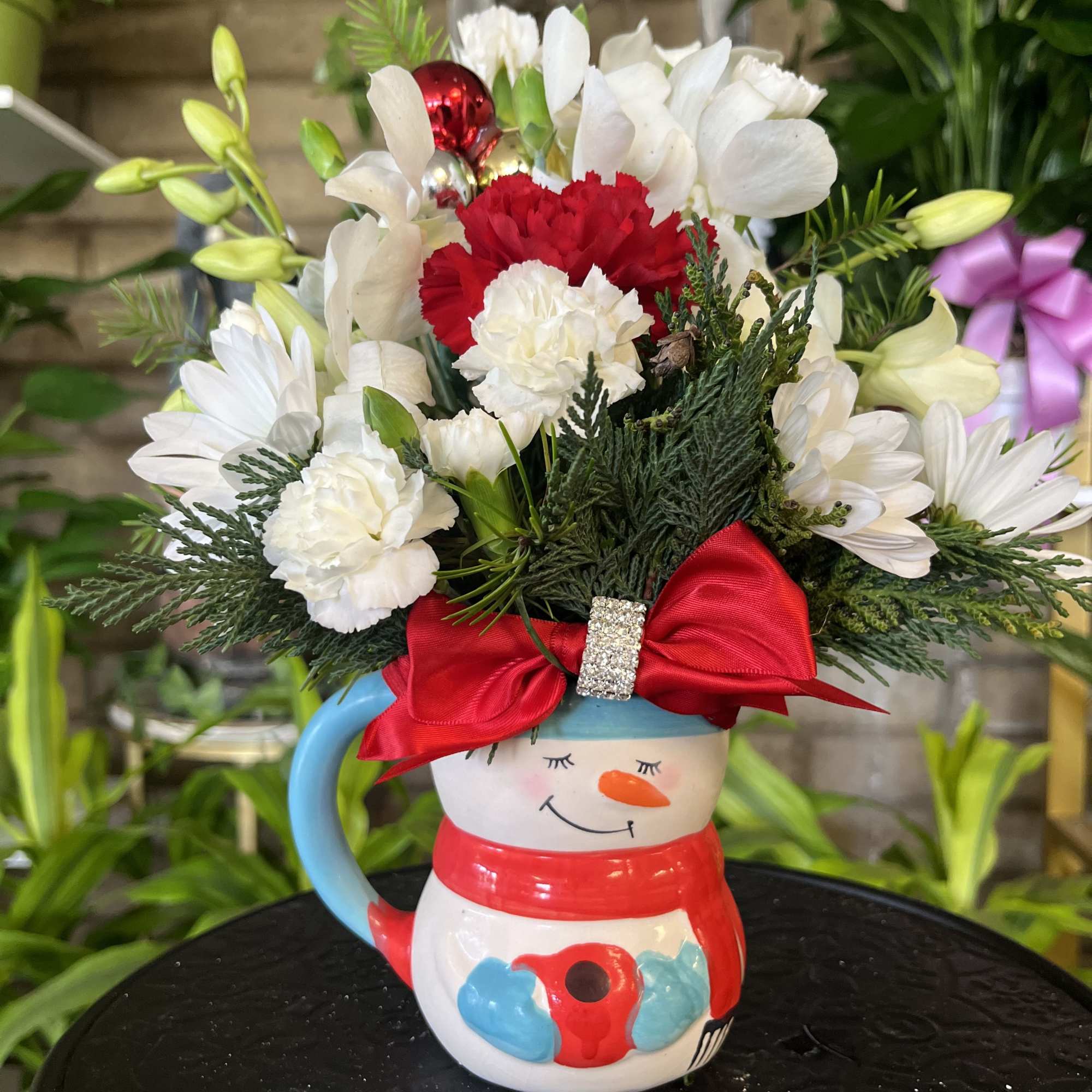 Snowman mug filled with white and red flowers and a red bow