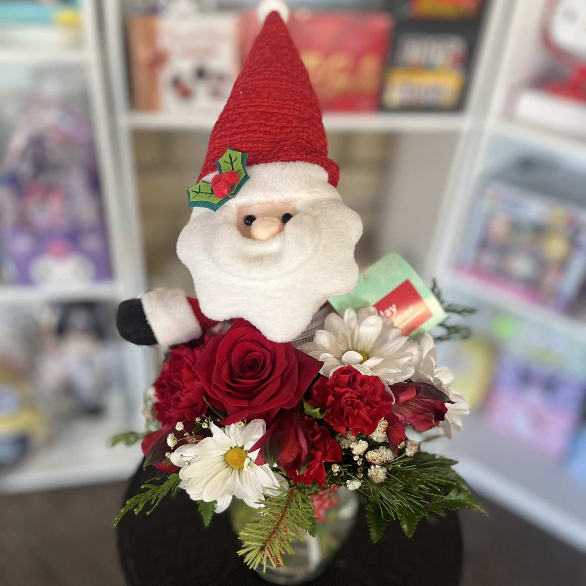 Santa figurine with red and white flowers in a vase