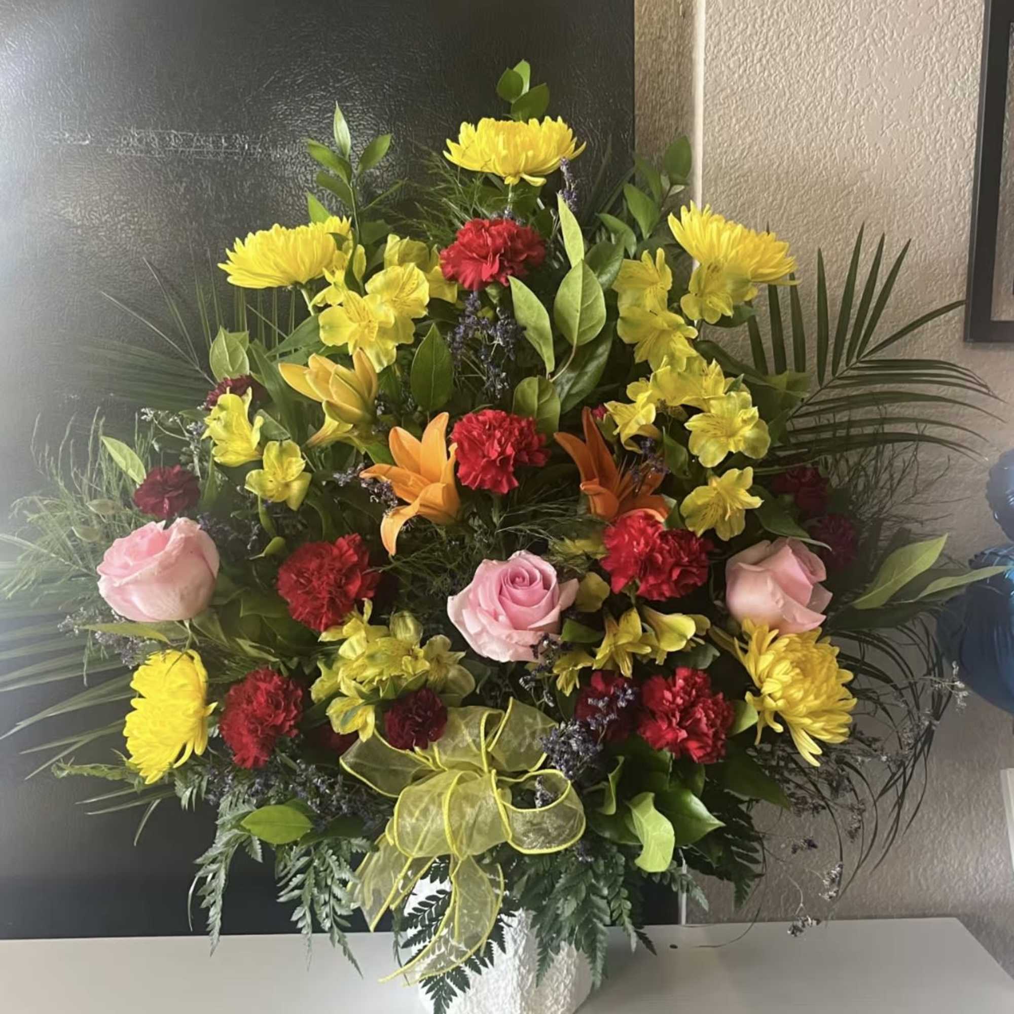 Mixed bouquet in a white vase with yellow, pink, red, and orange flowers