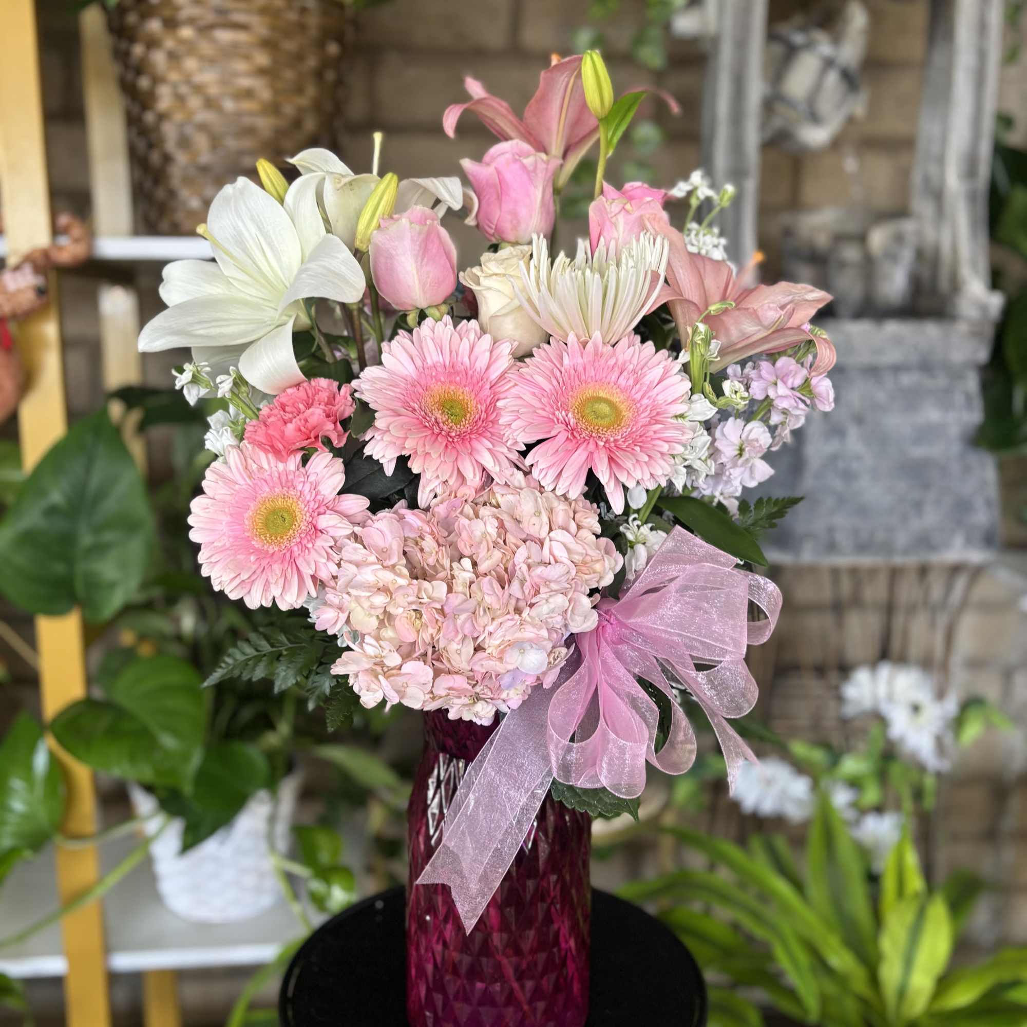Pink and white mixed bouquet in a magenta glass vase with a pink ribbon