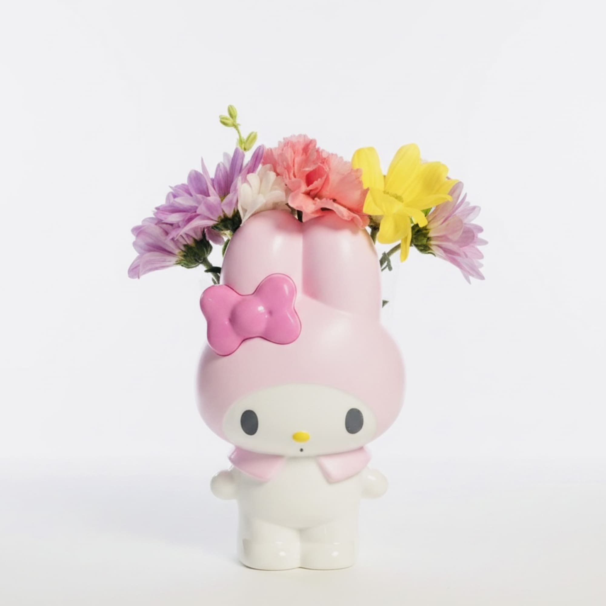 Pink Hello Kitty figurine holding a small bouquet of colorful flowers