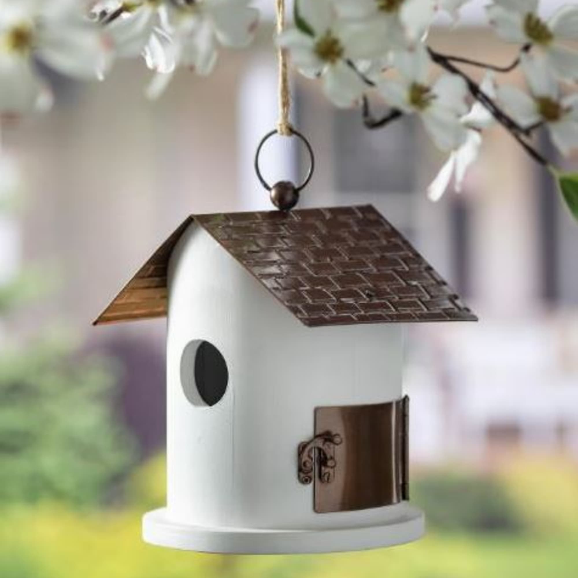 White hanging birdhouse with a brown roof and small round entrance