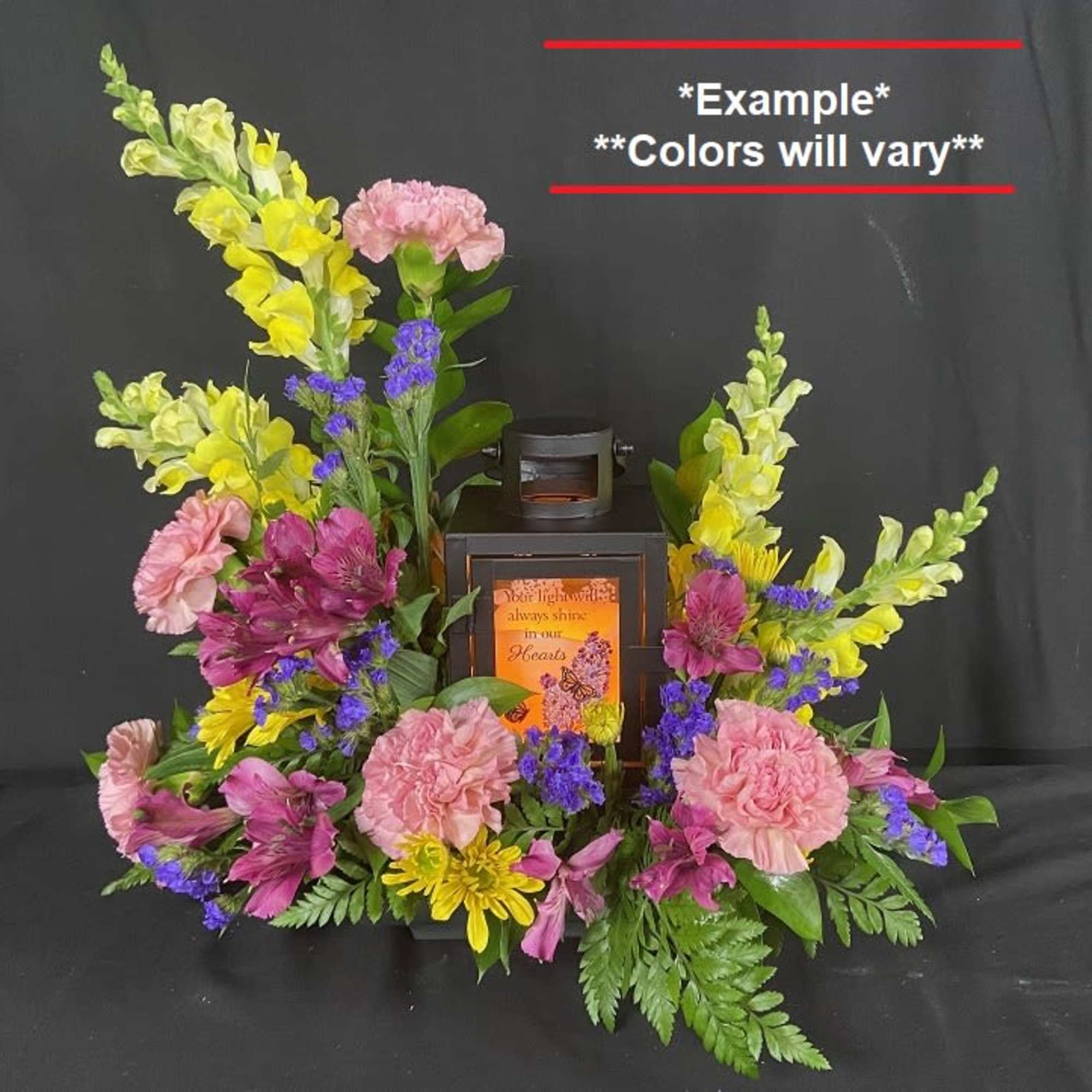 Floral arrangement around a black lantern with pink, yellow, and purple flowers.
