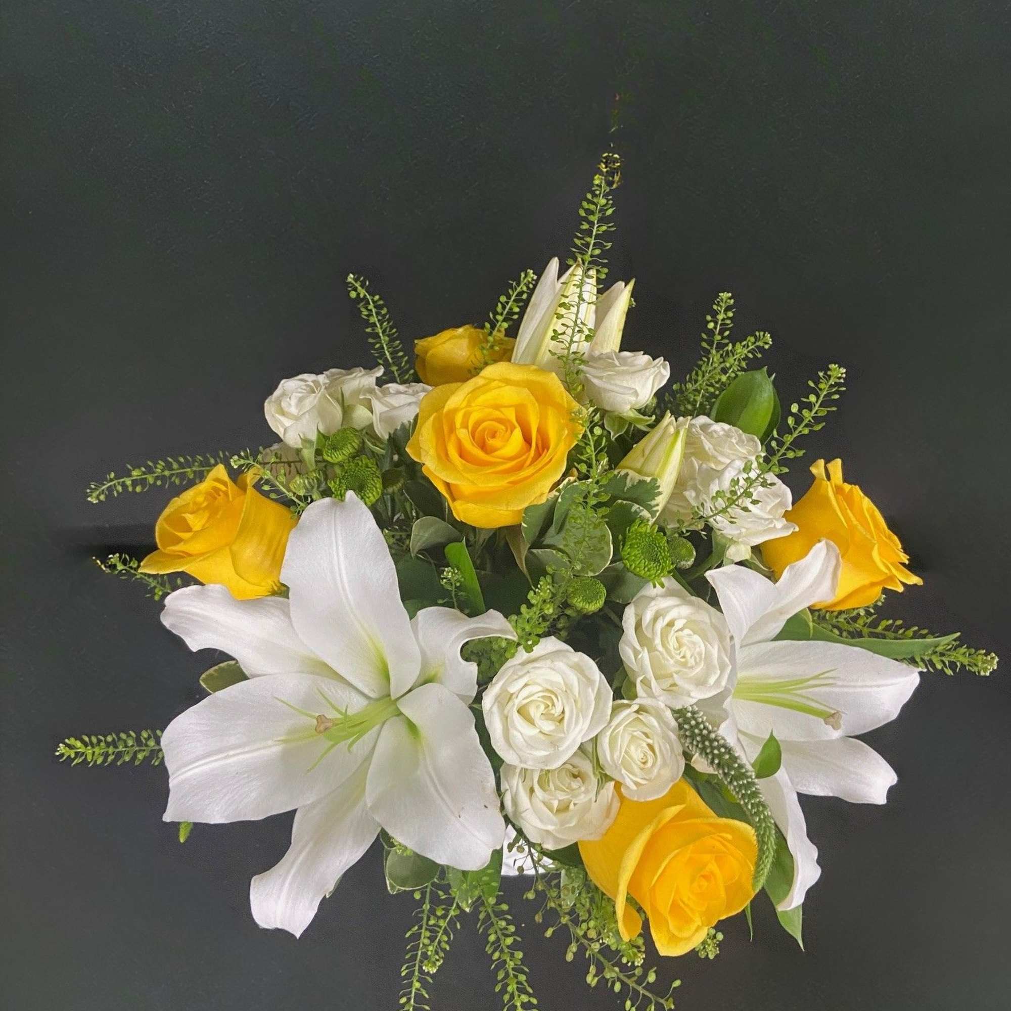 Yellow roses and white lilies arranged with white spray roses