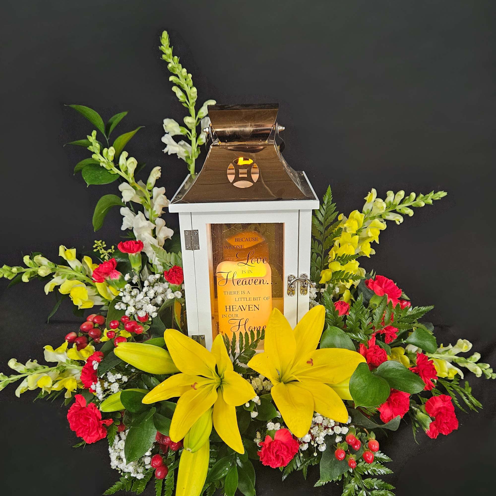 Floral lantern arrangement with yellow lilies, red carnations, and white blooms