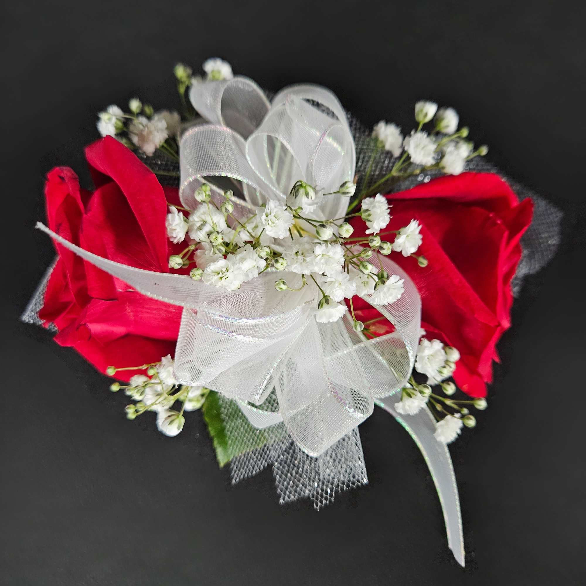 Red rose corsage with white baby's breath and a sheer ribbon bow