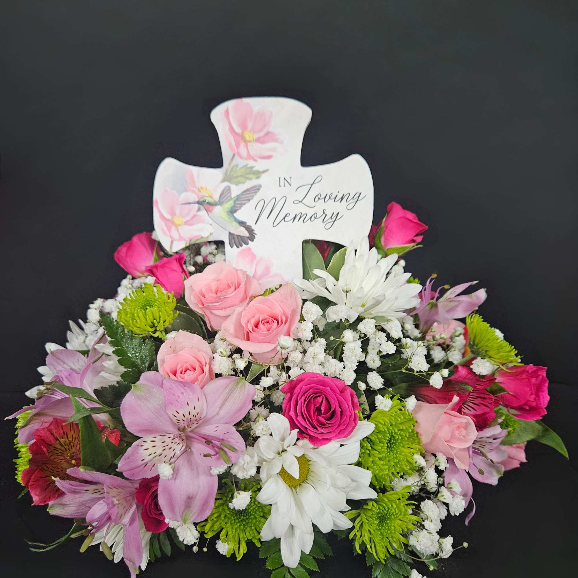 Sympathy floral arrangement with pink and white flowers around a memorial cross