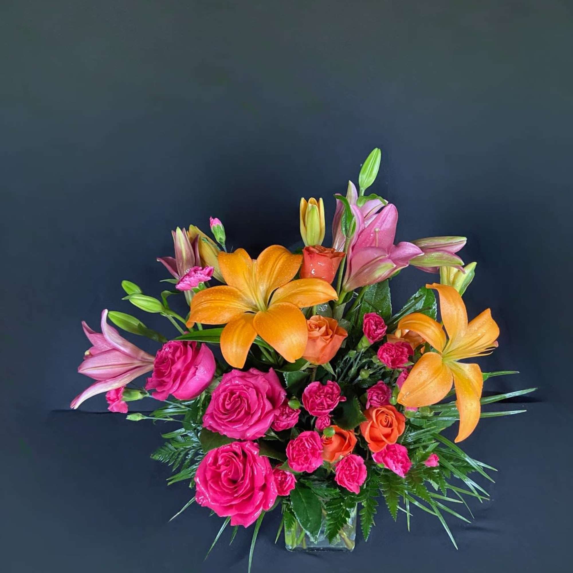 Bouquet of orange lilies and pink roses in a glass vase