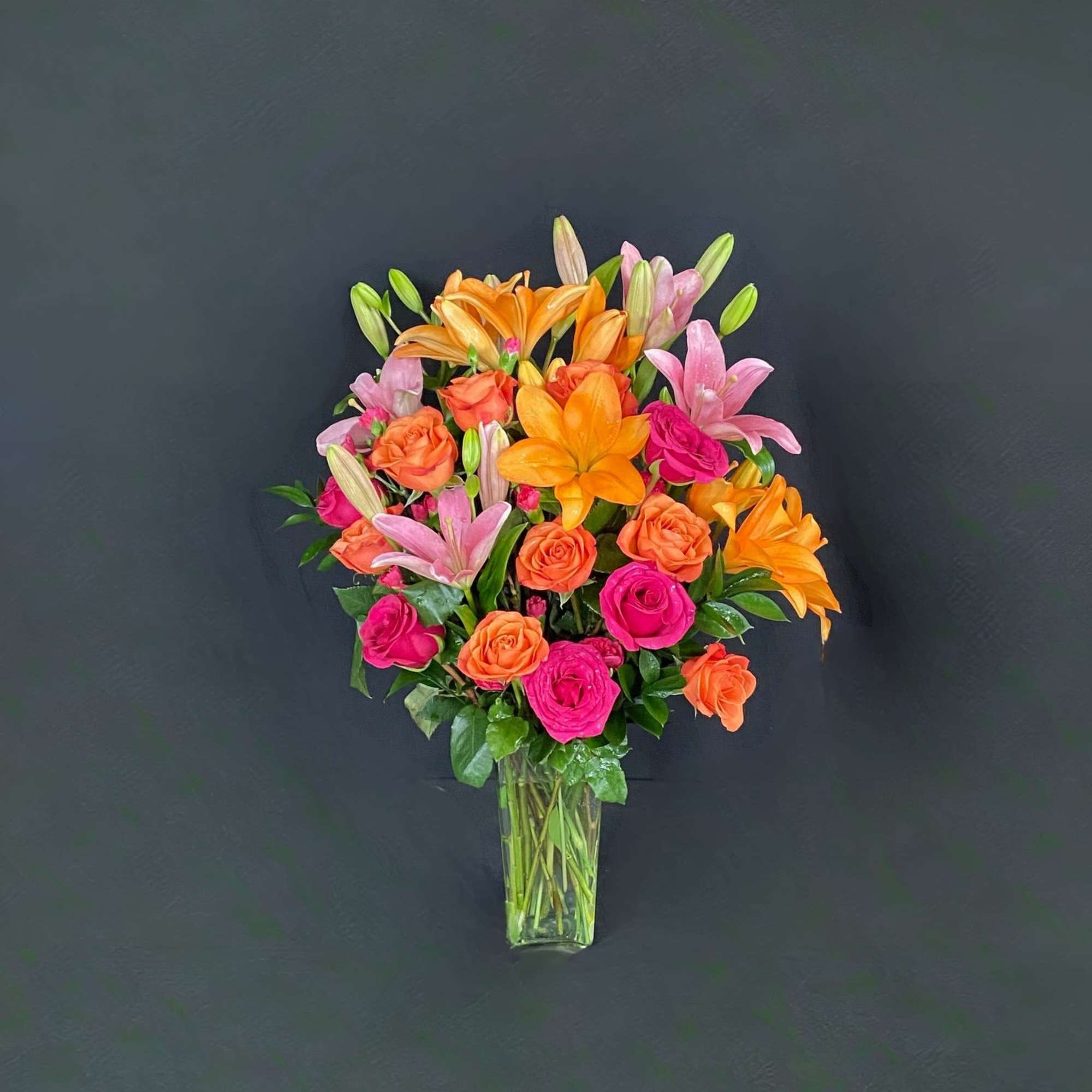 Bouquet of orange lilies and pink roses in a clear glass vase