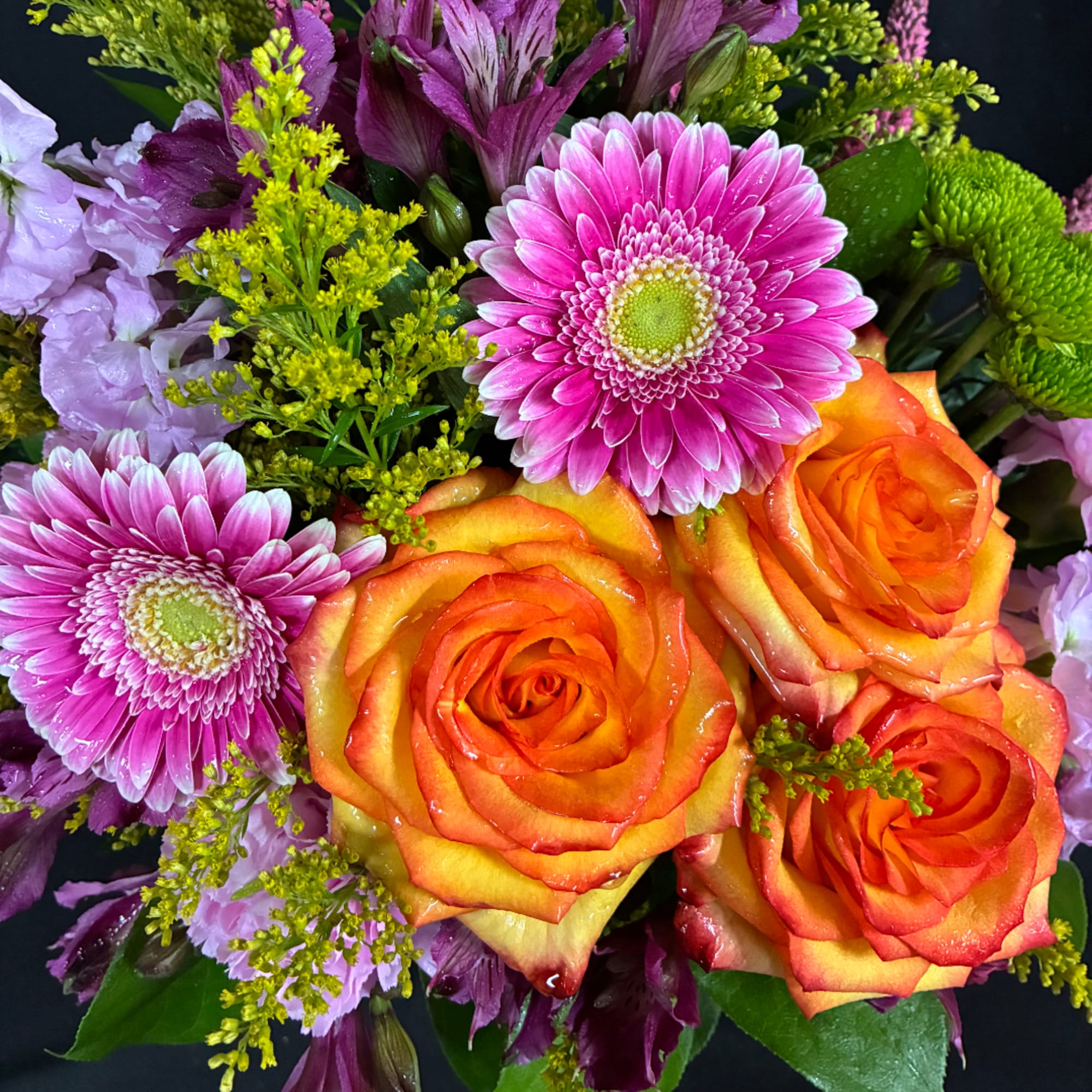 Bouquet of orange roses and pink daisies with purple blooms