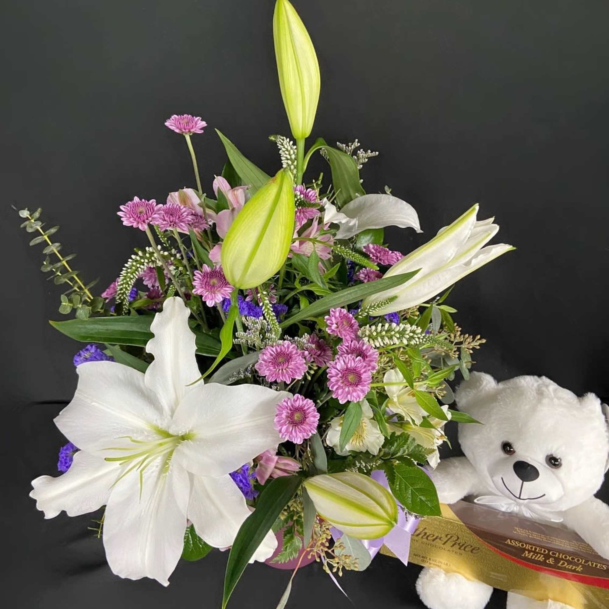 Bouquet of white lilies and pink daisies with a teddy bear and chocolates