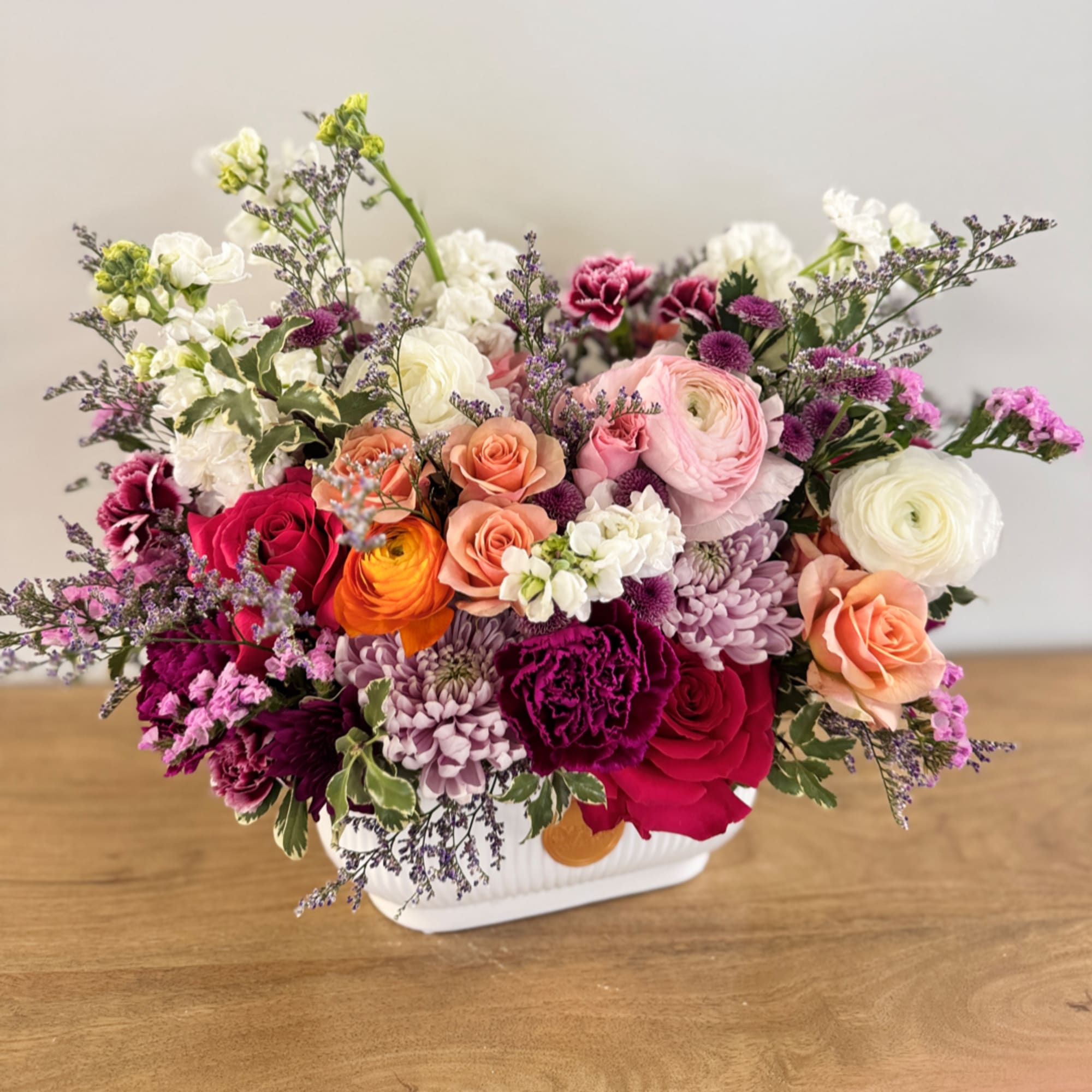 Mixed bouquet of roses, ranunculus, and chrysanthemums in a white vase