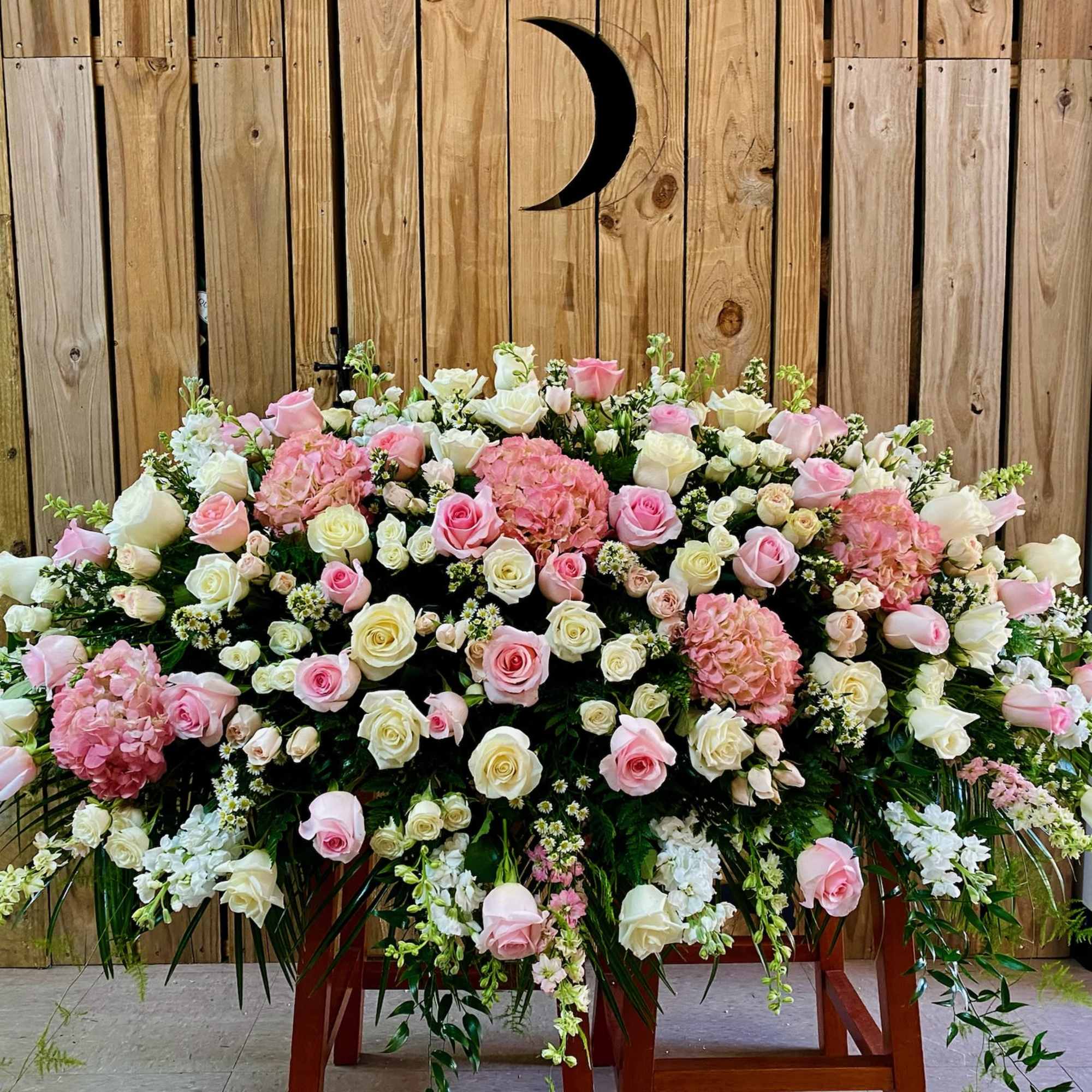 Large pink and white floral spray on a wooden stand