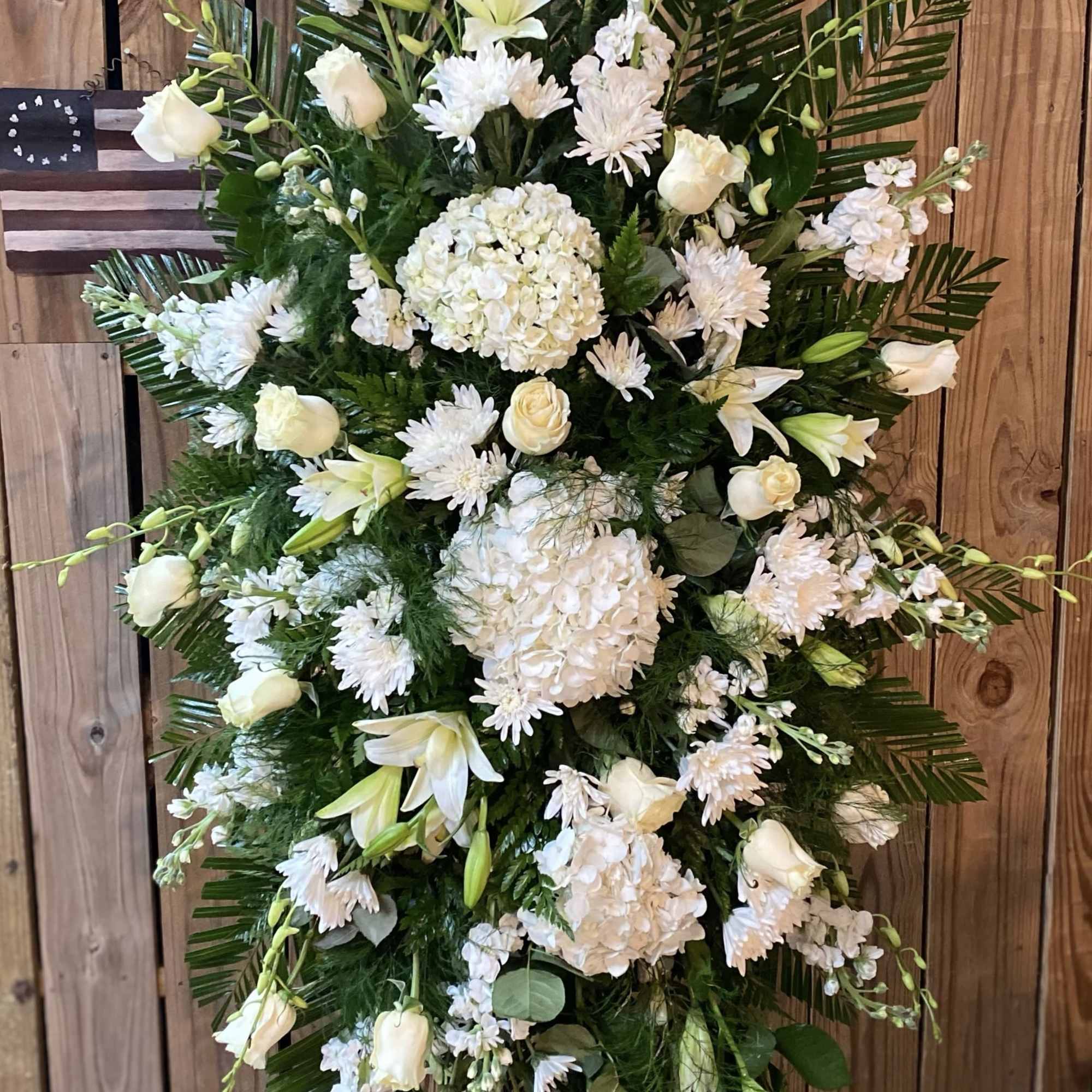 White funeral spray with roses, lilies, and hydrangeas on a stand