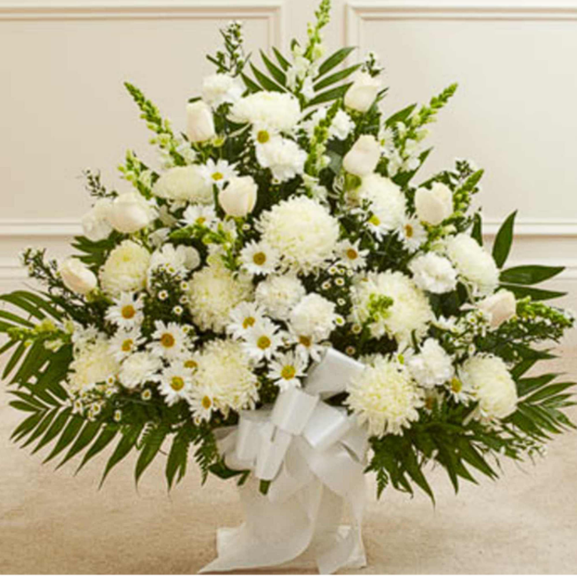 White floral arrangement with daisies, mums, and tulips in a white ribboned vase
