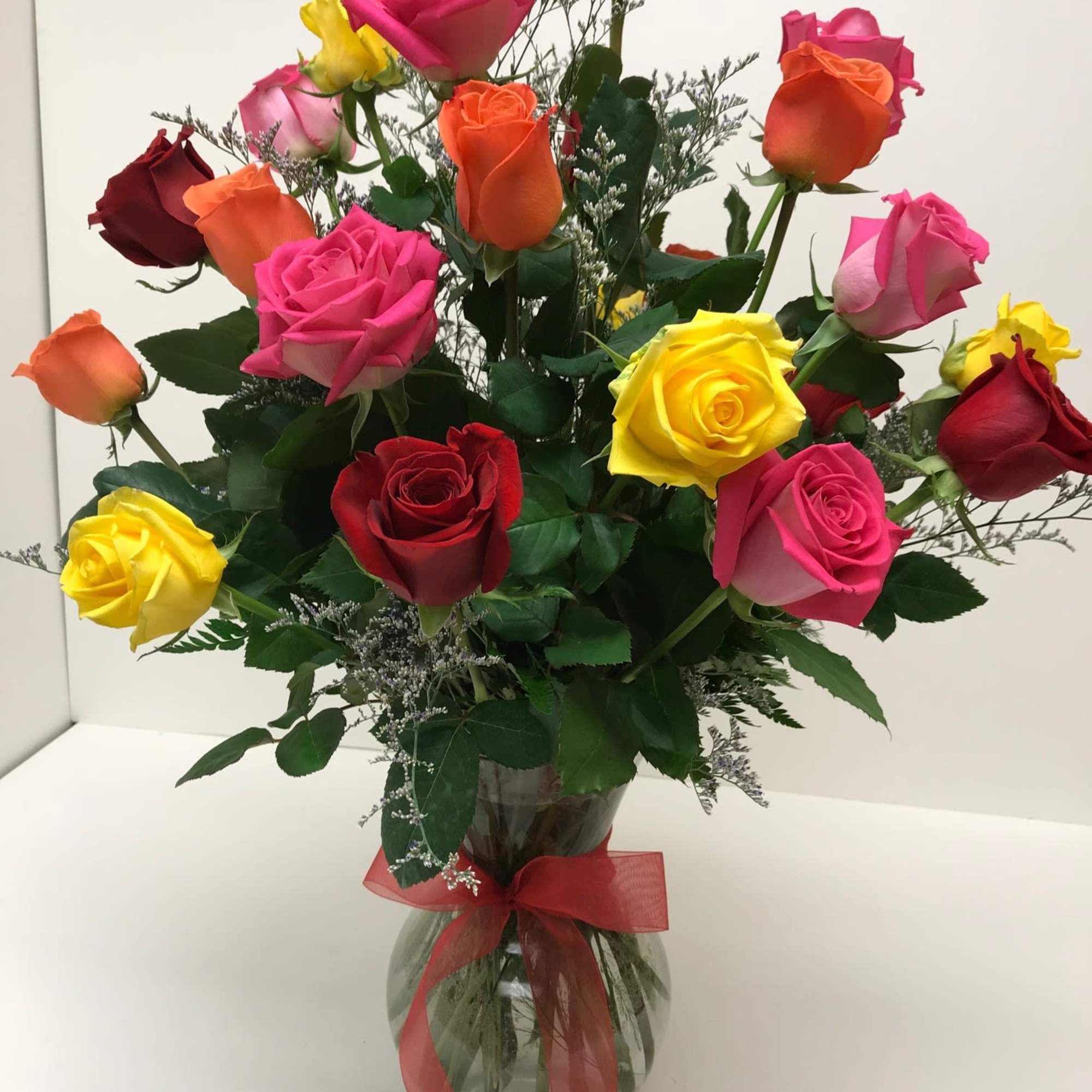 Mixed roses in a glass vase with a red ribbon