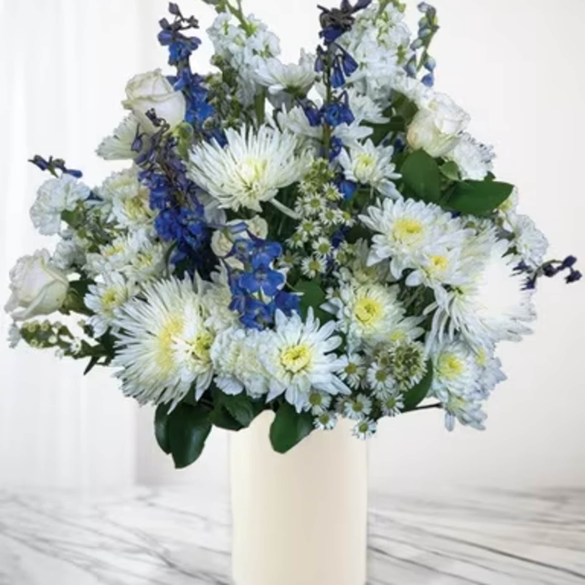 White and blue mixed flower arrangement in a tall vase