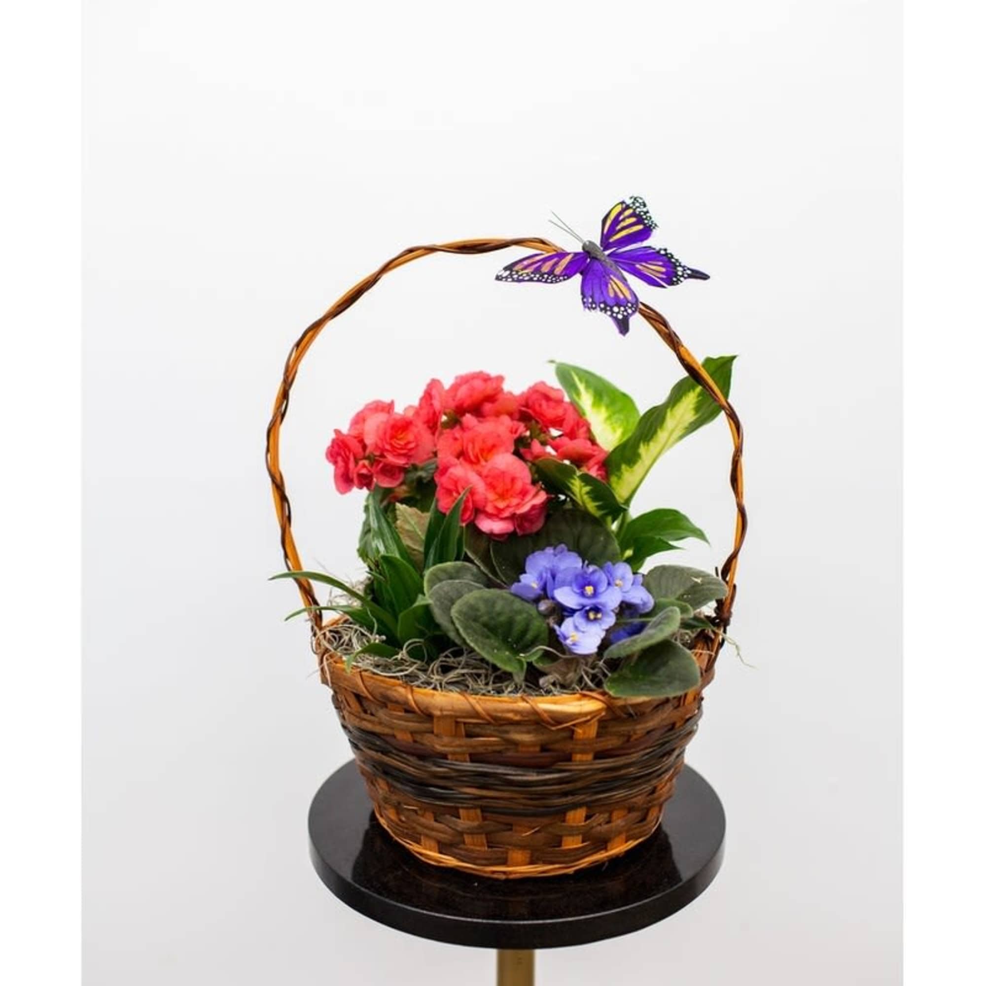 Basket of pink and purple flowers with a butterfly decoration