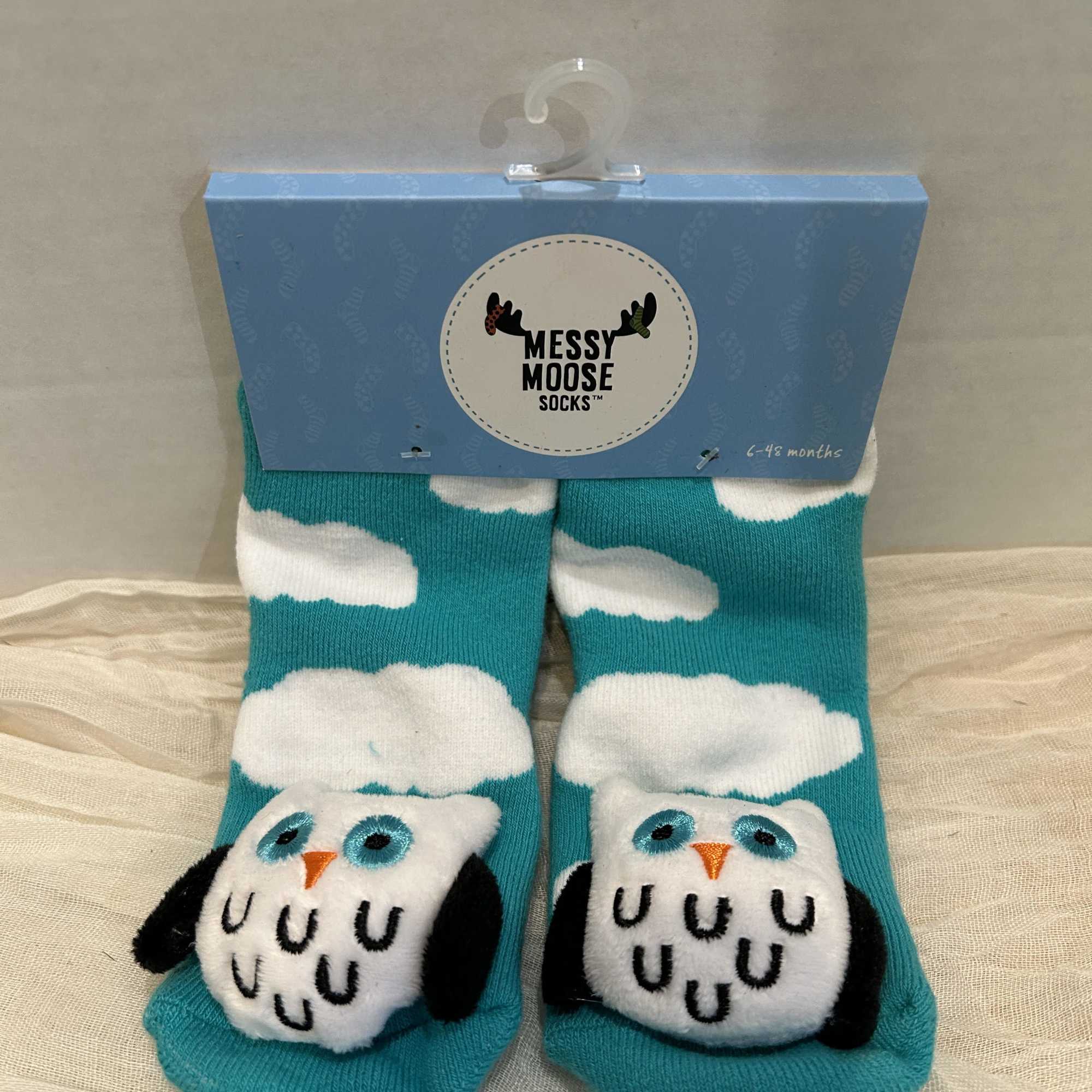 Pair of turquoise baby socks with owl faces in a blue package