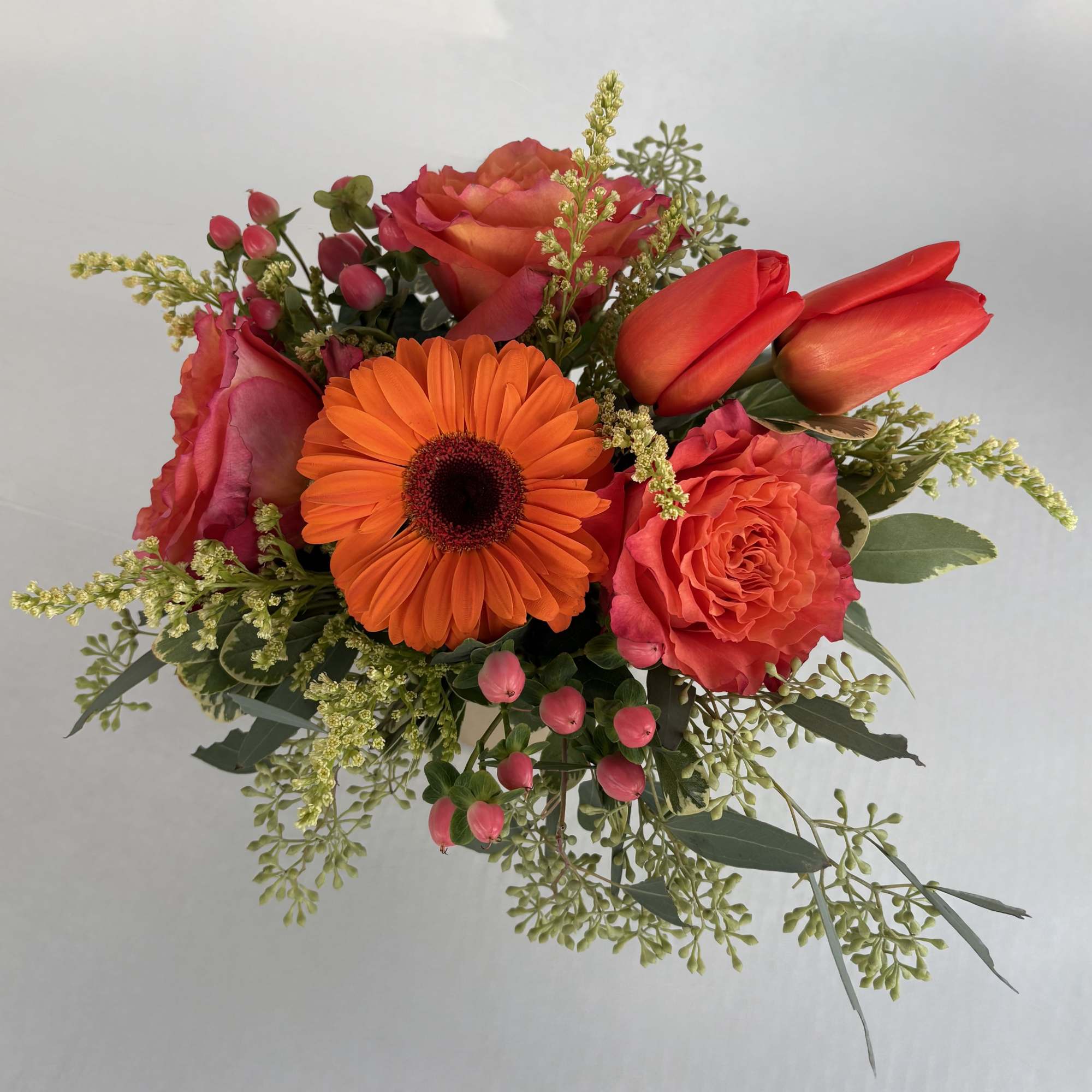 Bouquet of orange gerbera daisies, coral roses, and red tulips