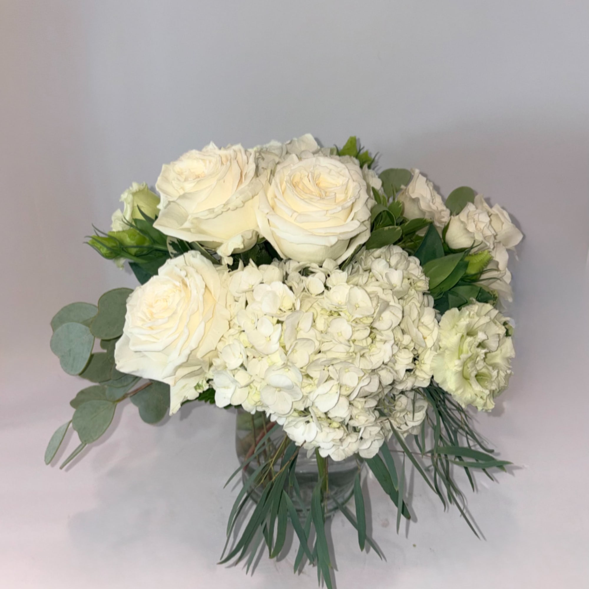 White roses and hydrangeas in a clear glass vase, photo 2 of 2