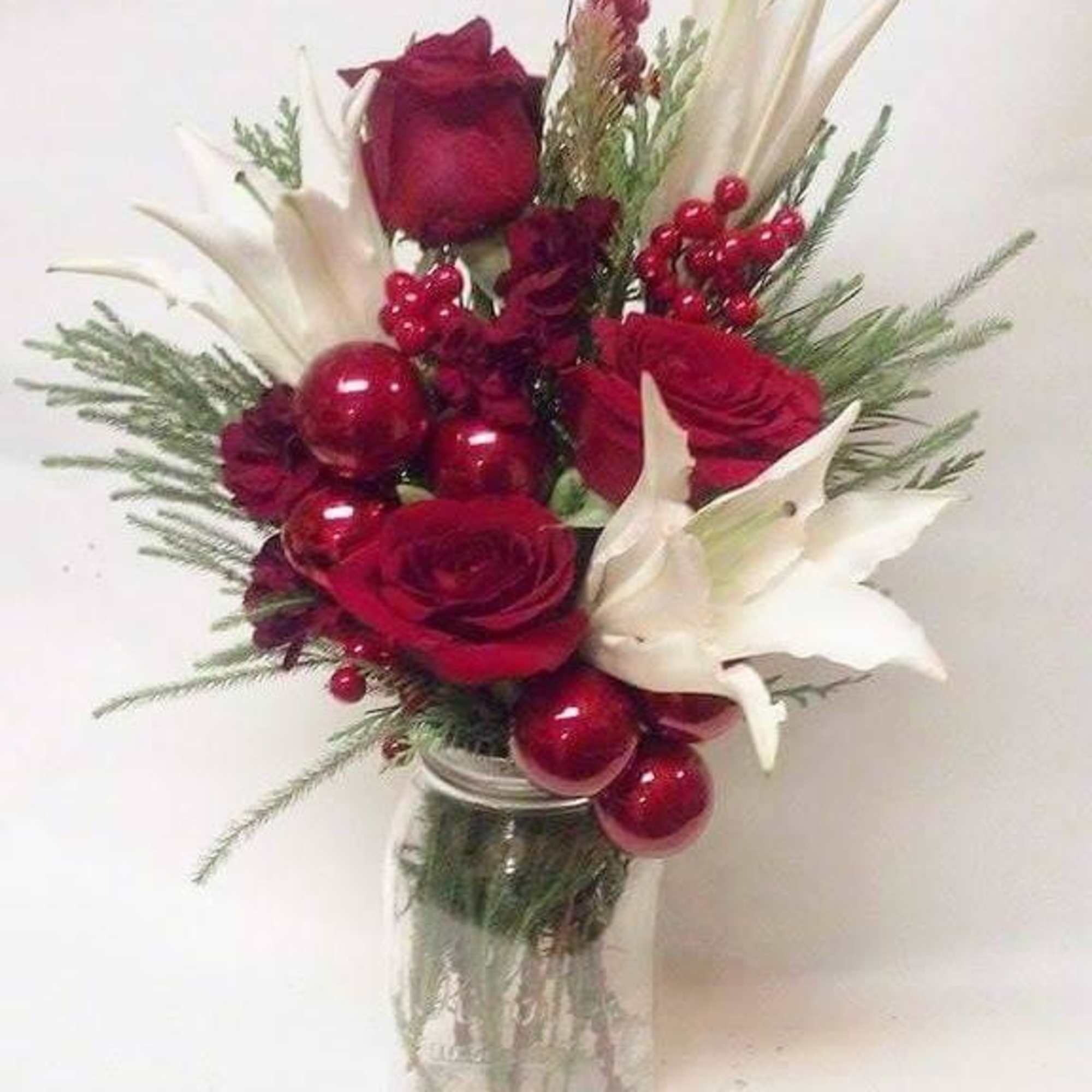 Roses, Mini carnations, festive berries and seasonal greens fill this mason jar