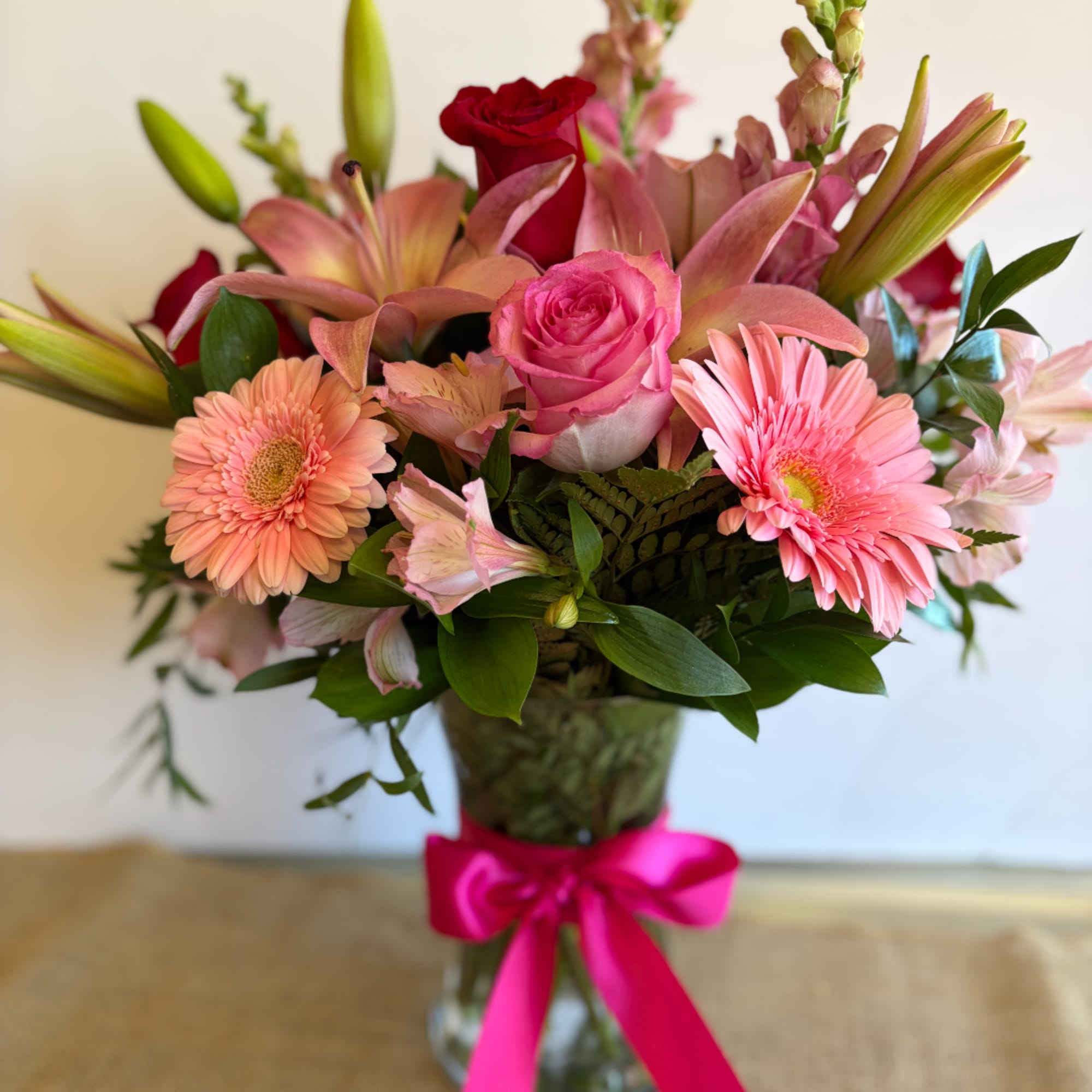 Pink and peach mixed bouquet in a glass vase with a bright ribbon