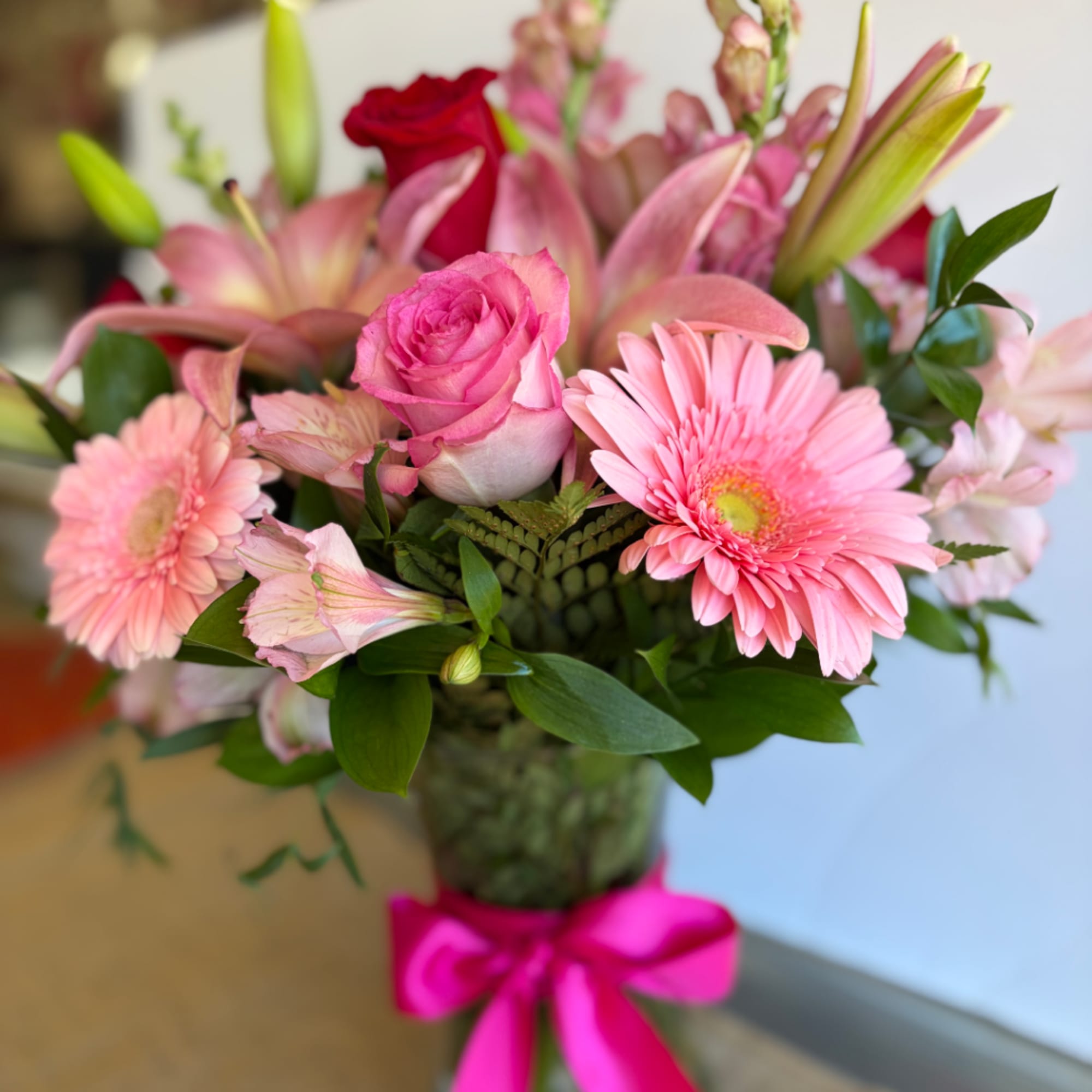 Pink bouquet with roses, lilies, and gerbera daisies in a glass vase