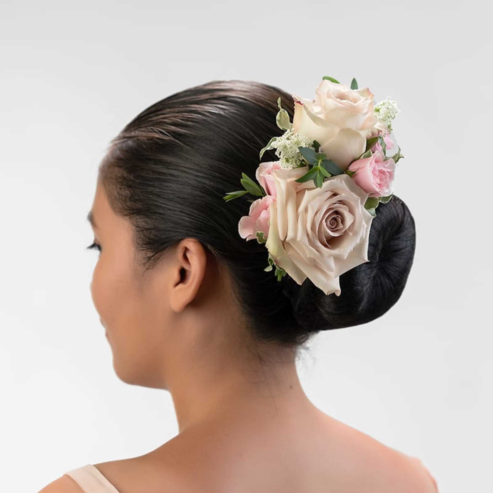 Blush and ivory rose hairpiece on a sleek dark bun, viewed from the back