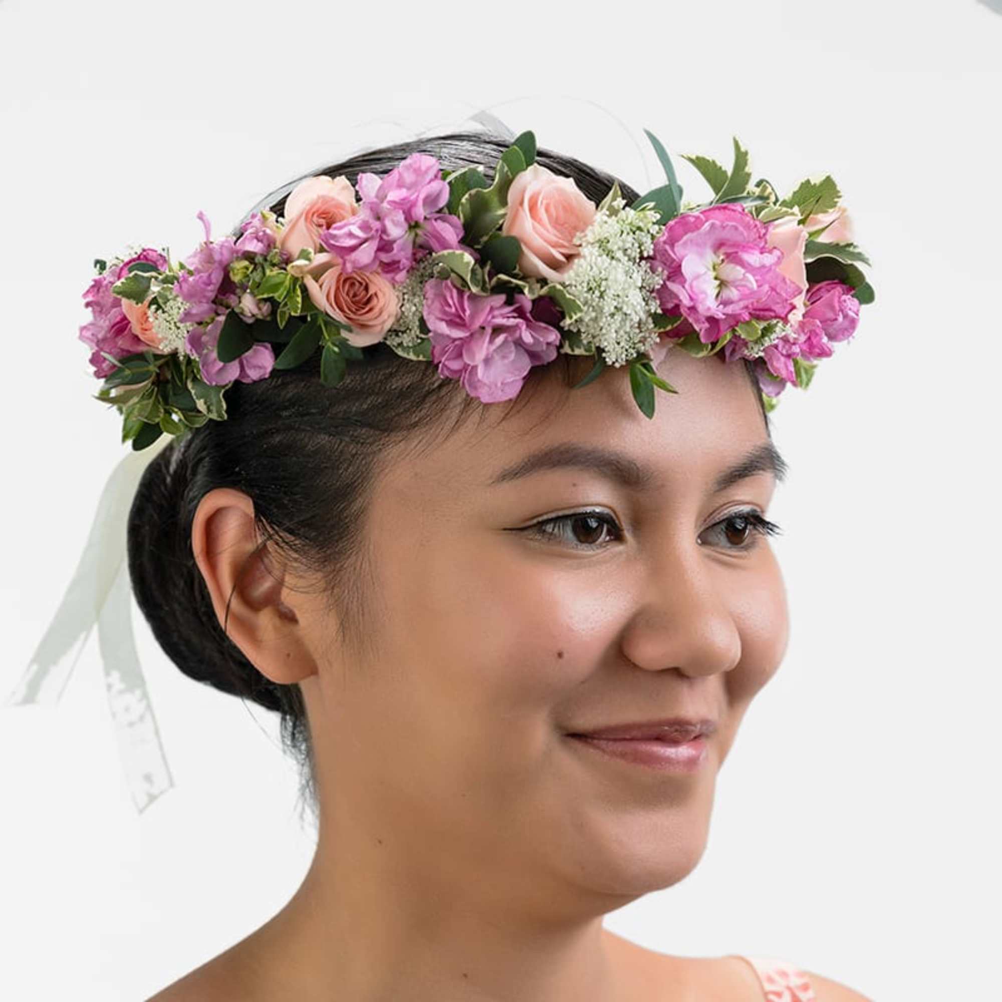 Pink and peach flower crown with ribbon worn on a woman's head